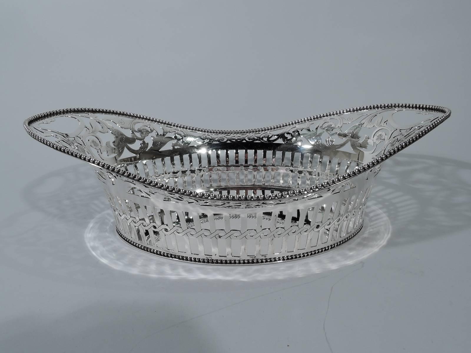 Victorian sterling silver basket. Made by Tiffany & Co. in New York, circa 1884. Solid oval well and swooping rim. Sides pierced: Colonnade bisected with guilloche band and surmounted by fluid scrollwork and flowers heightened with engraving. Open