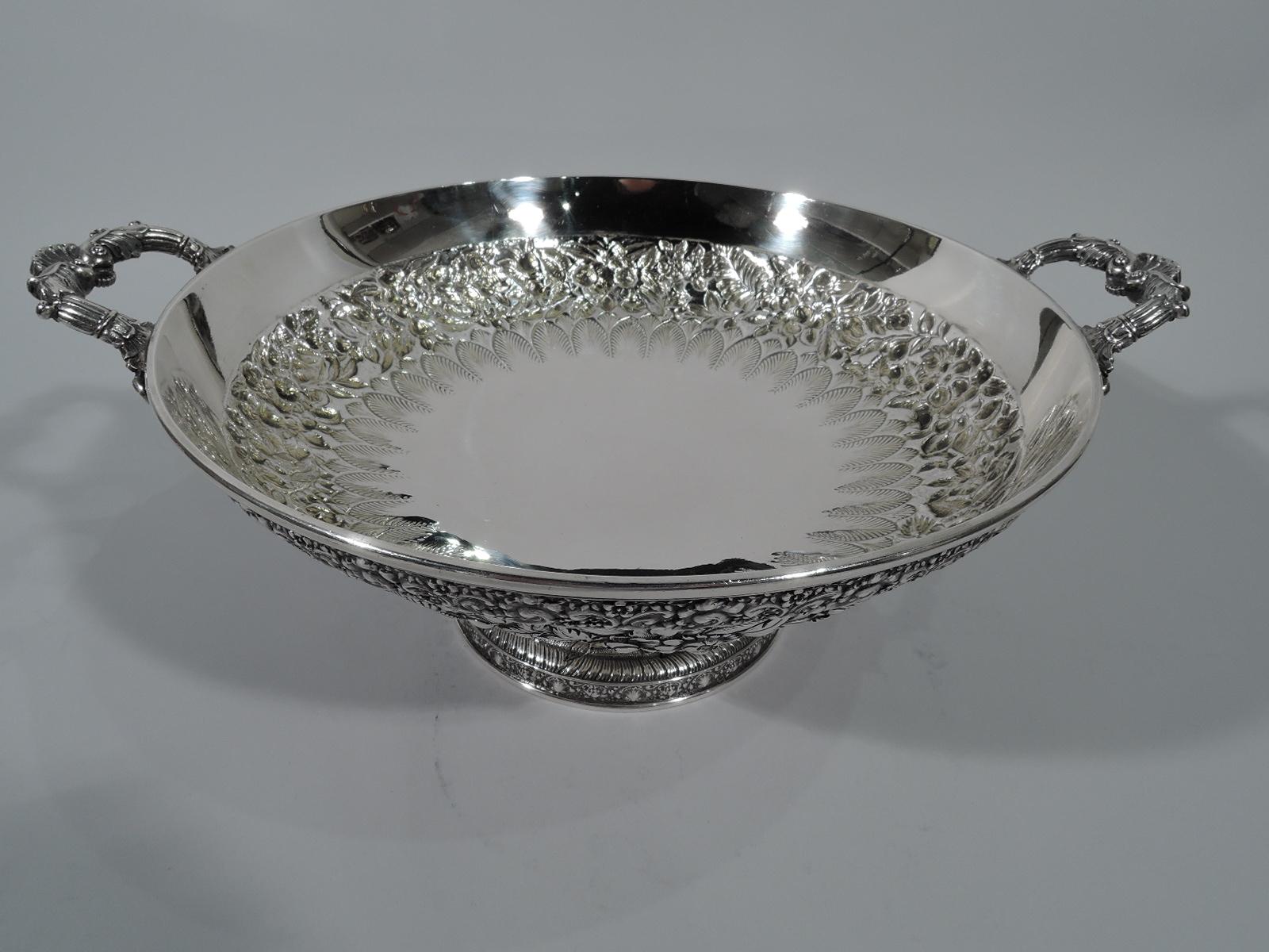 Classical sterling silver kylix with floral repousse. Made by Tiffany & Co. in New York. Traditional form with round and shallow bowl, leaf-mounted bracket handles, and raised foot. On exterior are bands of floral repousse and chased imbricated