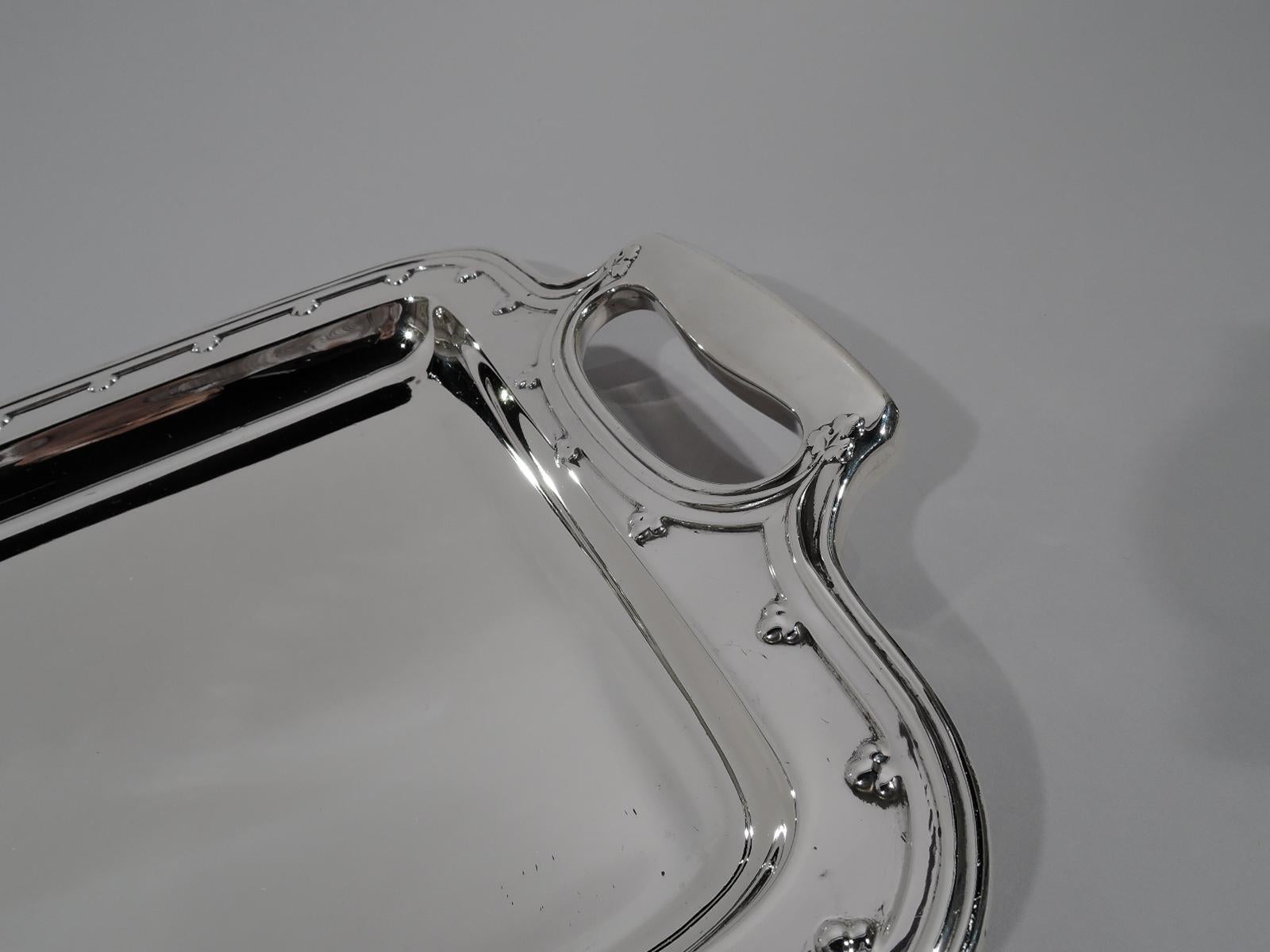 Saint Dunstan sterling silver bar tray. Made by Tiffany & Co. in New York, circa 1910. Deep rectangular well with round corners. Shoulder flat with applied fleurs-de-lys. Rim molded. Cutout kidney-form bracket end handles. A beautiful piece in this