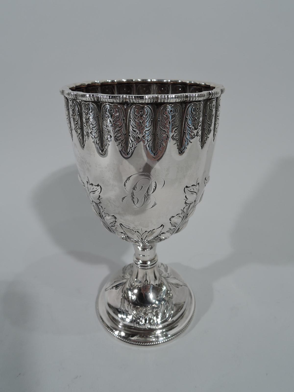 Early sterling silver goblet. Retailed by Tiffany & Co. at 550 Broadway, New York. Ovoid bowl with half-lobbing and scalloped rim on knopped stem terminating in domed foot. Engraved and repousse flowers and foliage. Script monogram. A fancy piece by