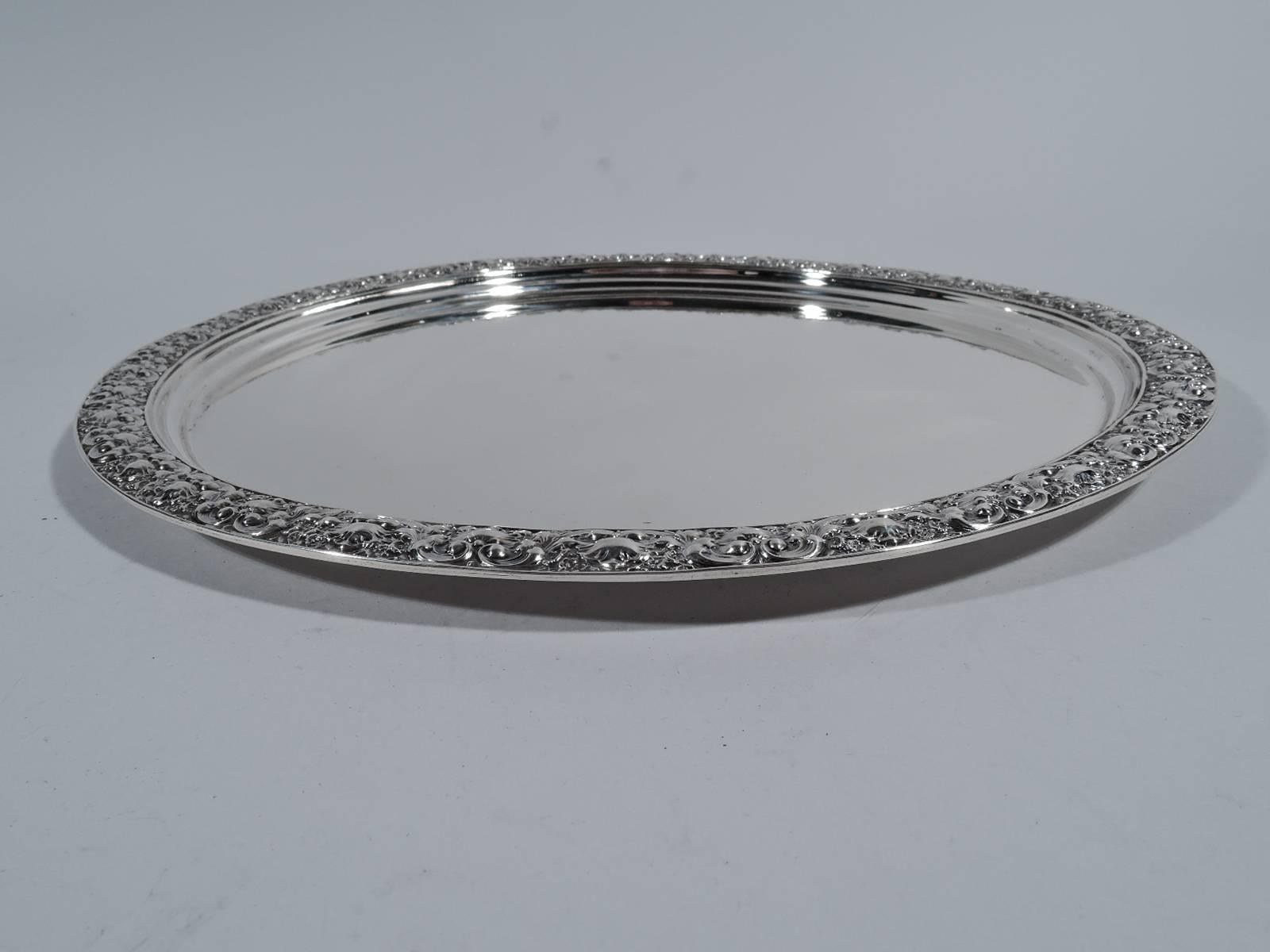 Sterling silver serving tray. Made by Tiffany & Co. in New York. Plain circular well. Rim has dense ornament with alternating scallop sells and scrolls. Hallmark includes no. 5766 and director’s letter T (1892-1902). Weight: 24.5 troy ounces.