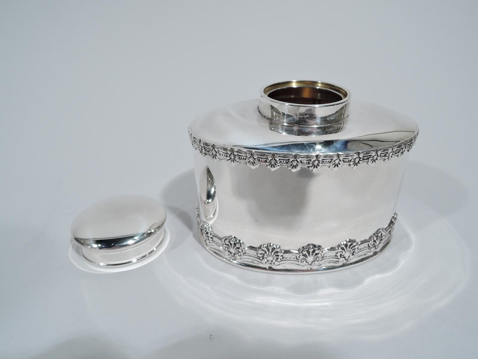 English king sterling silver tea caddy. Made by Tiffany & Co. in New York. Oval with straight sides, curved top, and short inset neck with cover. Sides have ornamental border applied to top and bottom comprising alternating scallop shells and