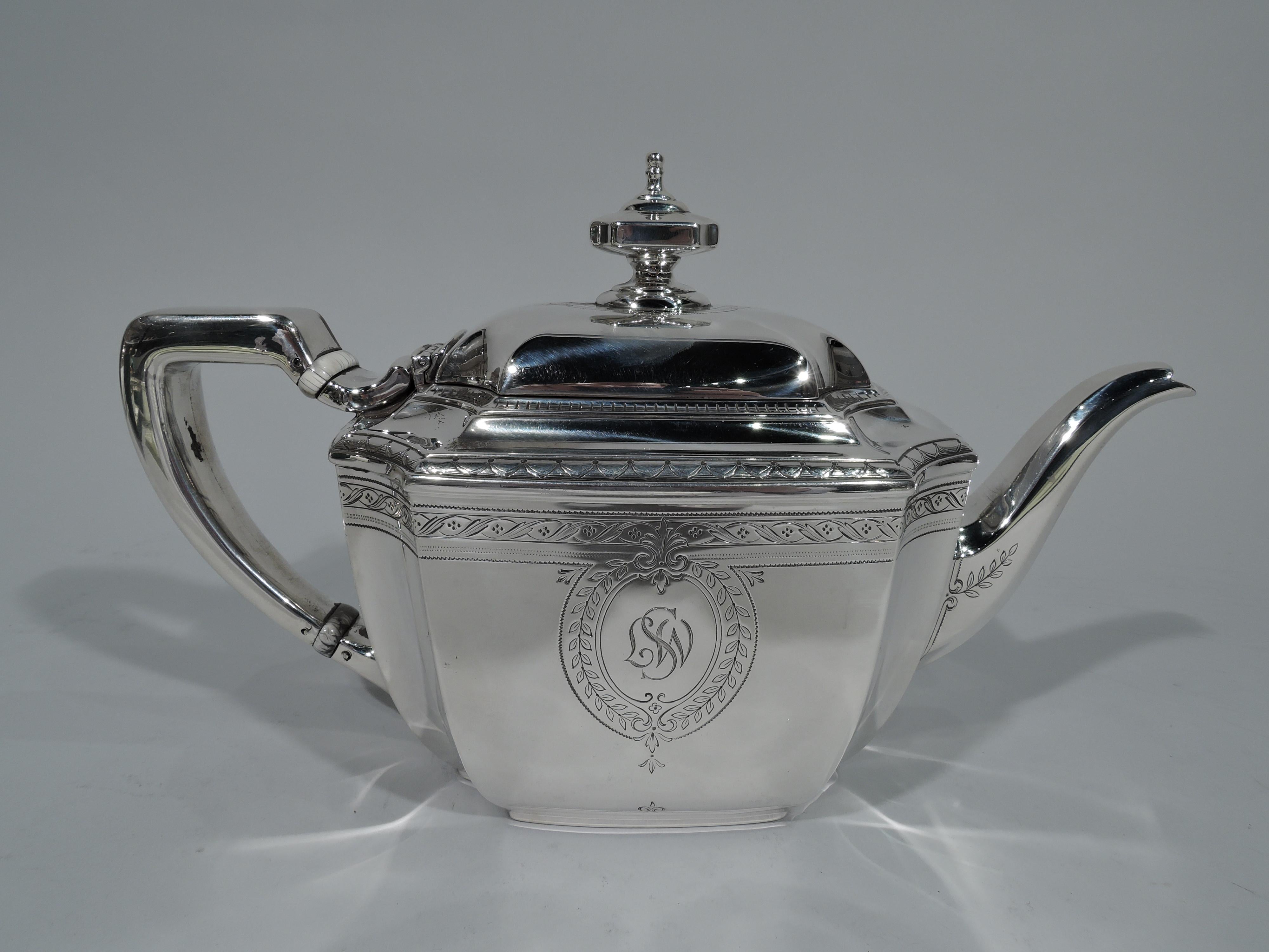 Classic sterling silver teapot in engraved Hampton pattern. Made by Tiffany & Co. in New York, ca 1912. Rectilinear with tapering sides, concave corners, and stepped rim. Cover hinged and raised with vase finial. Scroll bracket-handle and faceted