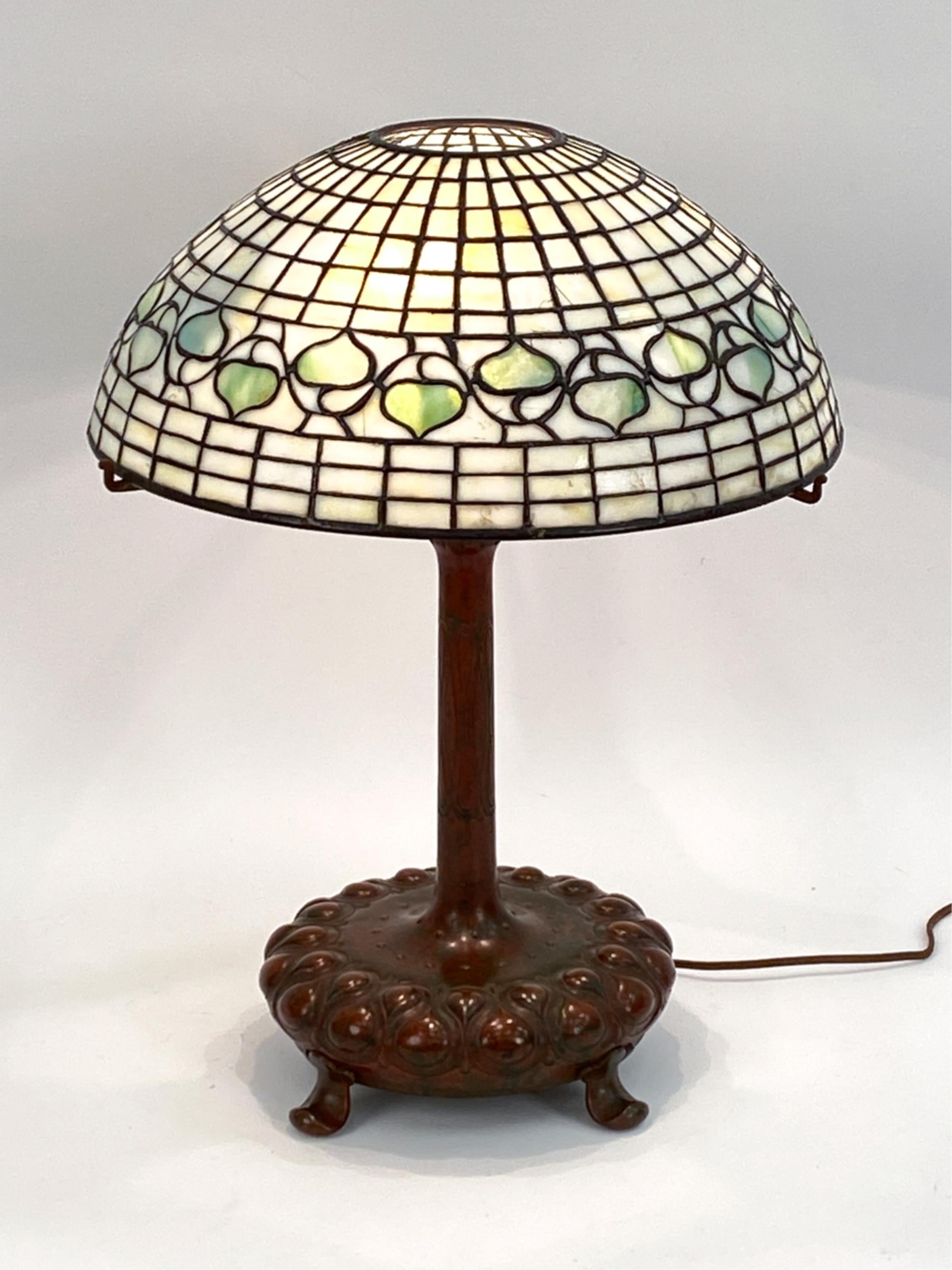 This lamp is a elegant testament to the classic Tiffany Studios design. Crafted in early 20th century, this lamp is evocative of the Art Nouveau style that Tiffany lamps are known for. This lamp is an original design, one that has been reproduced by