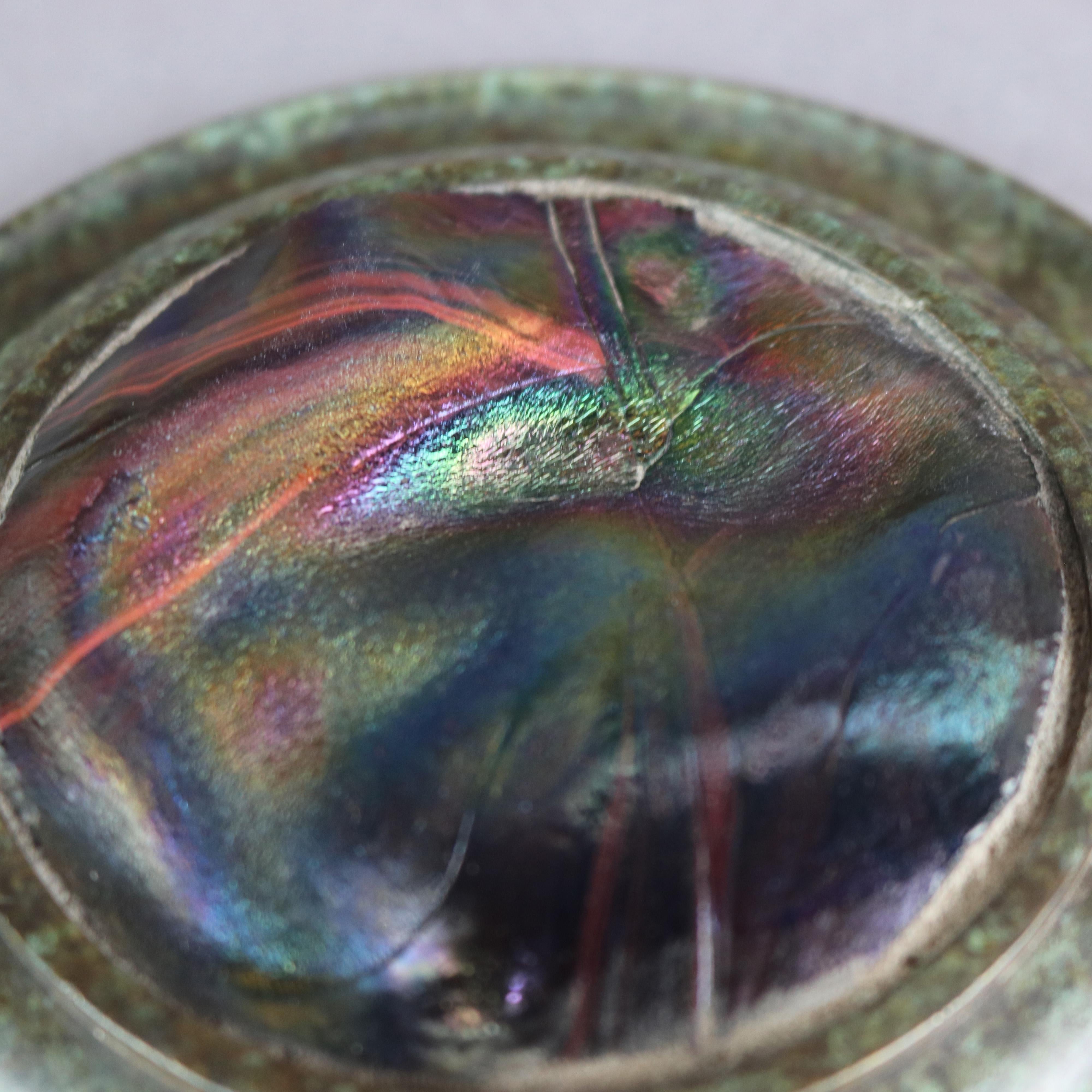 An antique paperweight in the manner of Tiffany Studios offers bronze circular stepped frame having slight well and reeded edge and housing art glass medallion, en verso later stamped 