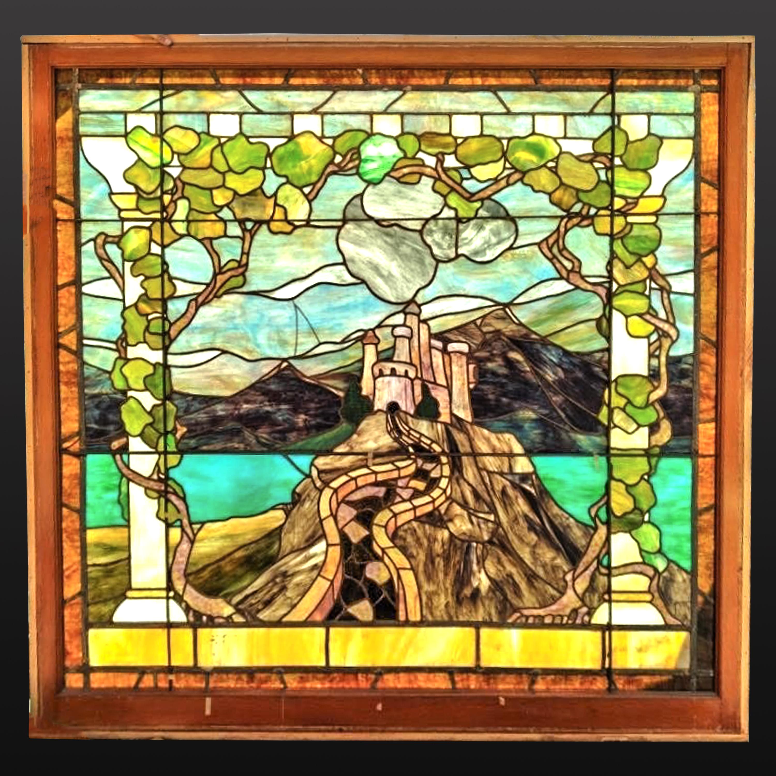 A highly important monumental American Arts & Crafts landscape window, attributed to Tiffany & Co, New York, Circa 1910.
The window having a border with textured gold tone tiles, the background is composed of variegated blue glass, with a mountain