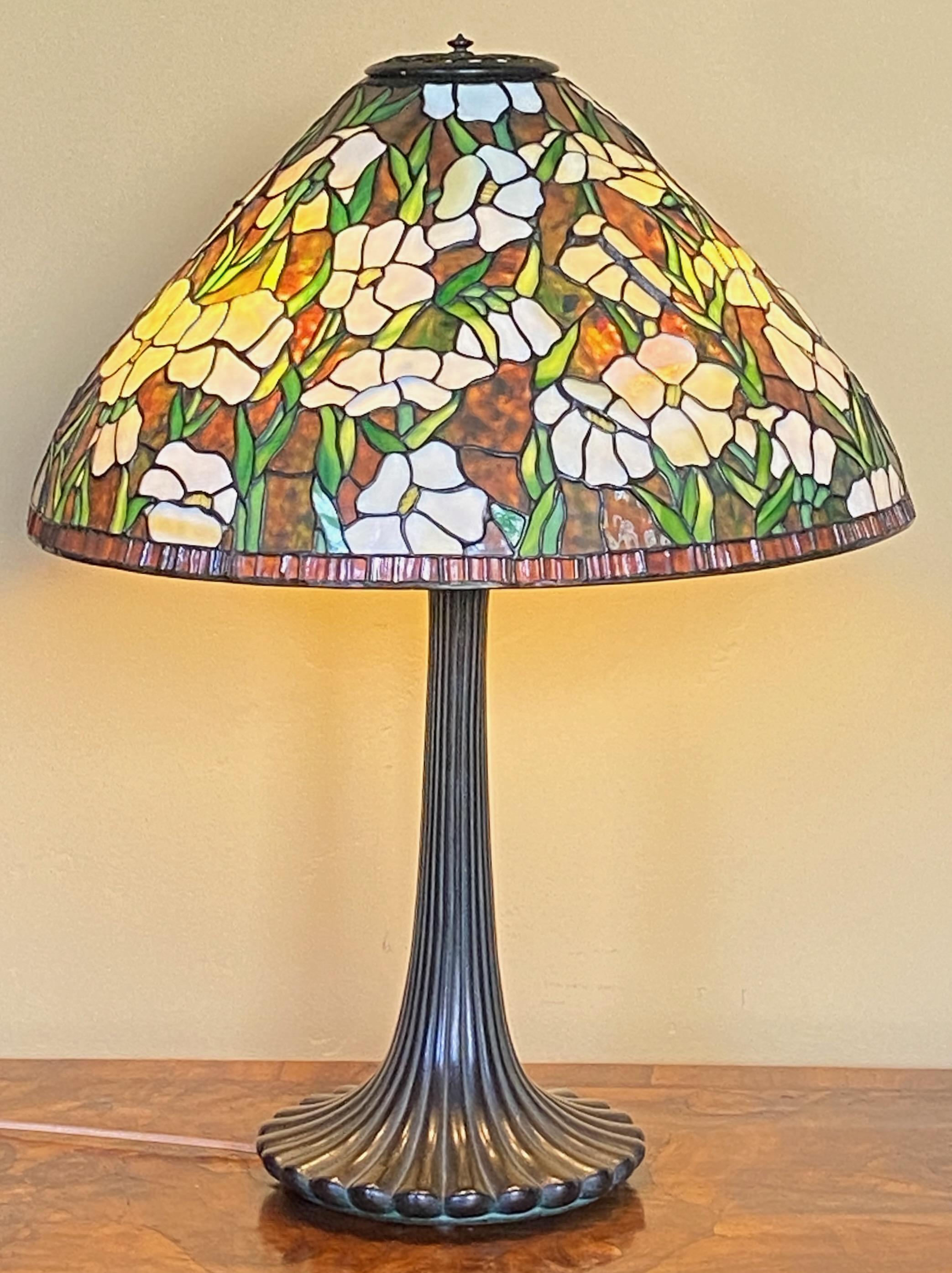 A Tiffany style table lamp with antique metal base and high quality leaded glass shade. Superb colors of glass in a floral motif - 
Overall in very good antique condition, there are a couple of minor cracks in a few piece of glass (please see all
