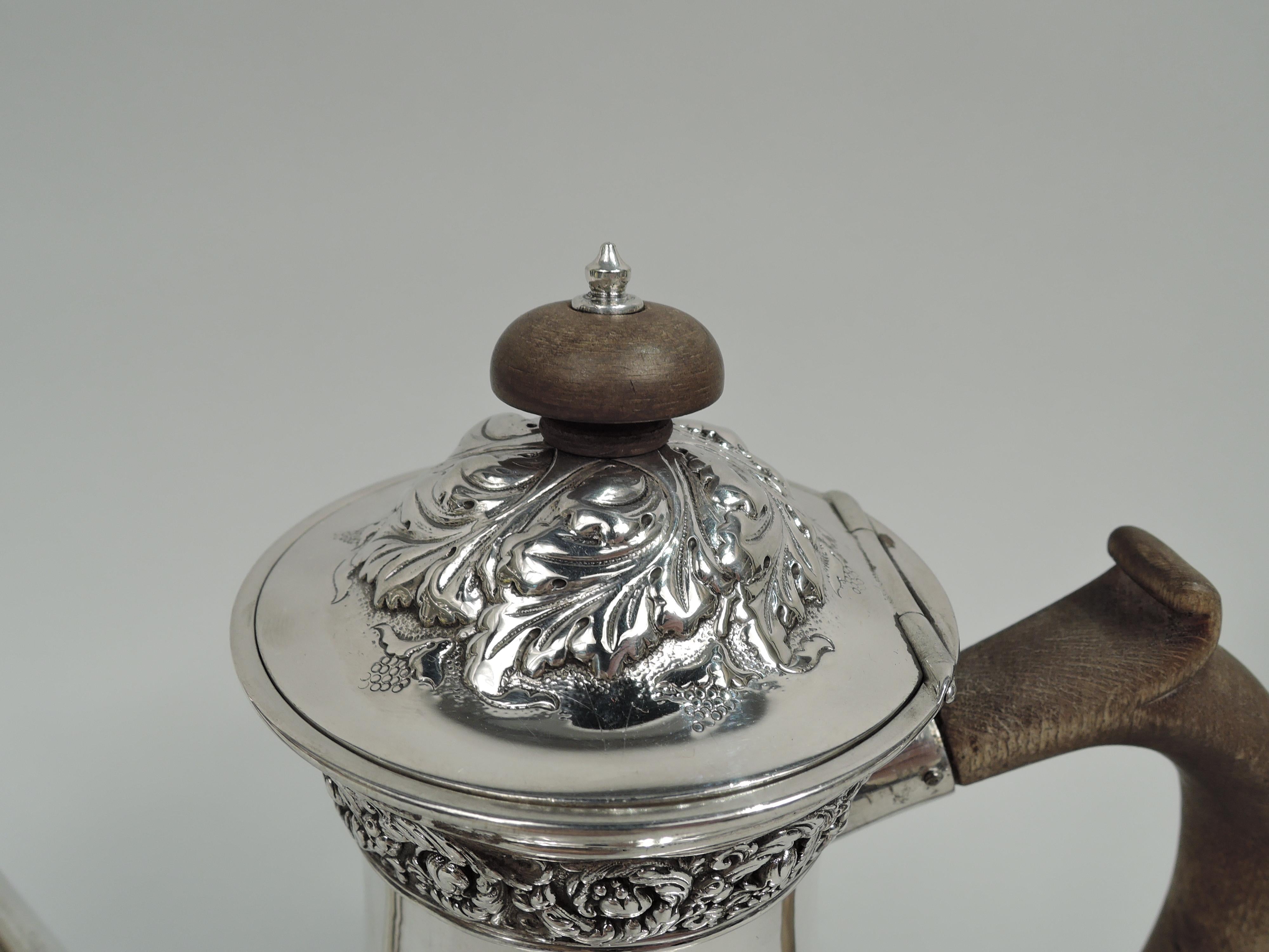 Victorian Classical sterling silver coffeepot. Made by Tiffany & Co. in New York. Baluster with vertical spout and hinged and domed cover. Stained-wood finial and capped scroll handle. Repousse rinceaux bands and applied gadrooned borders on body;