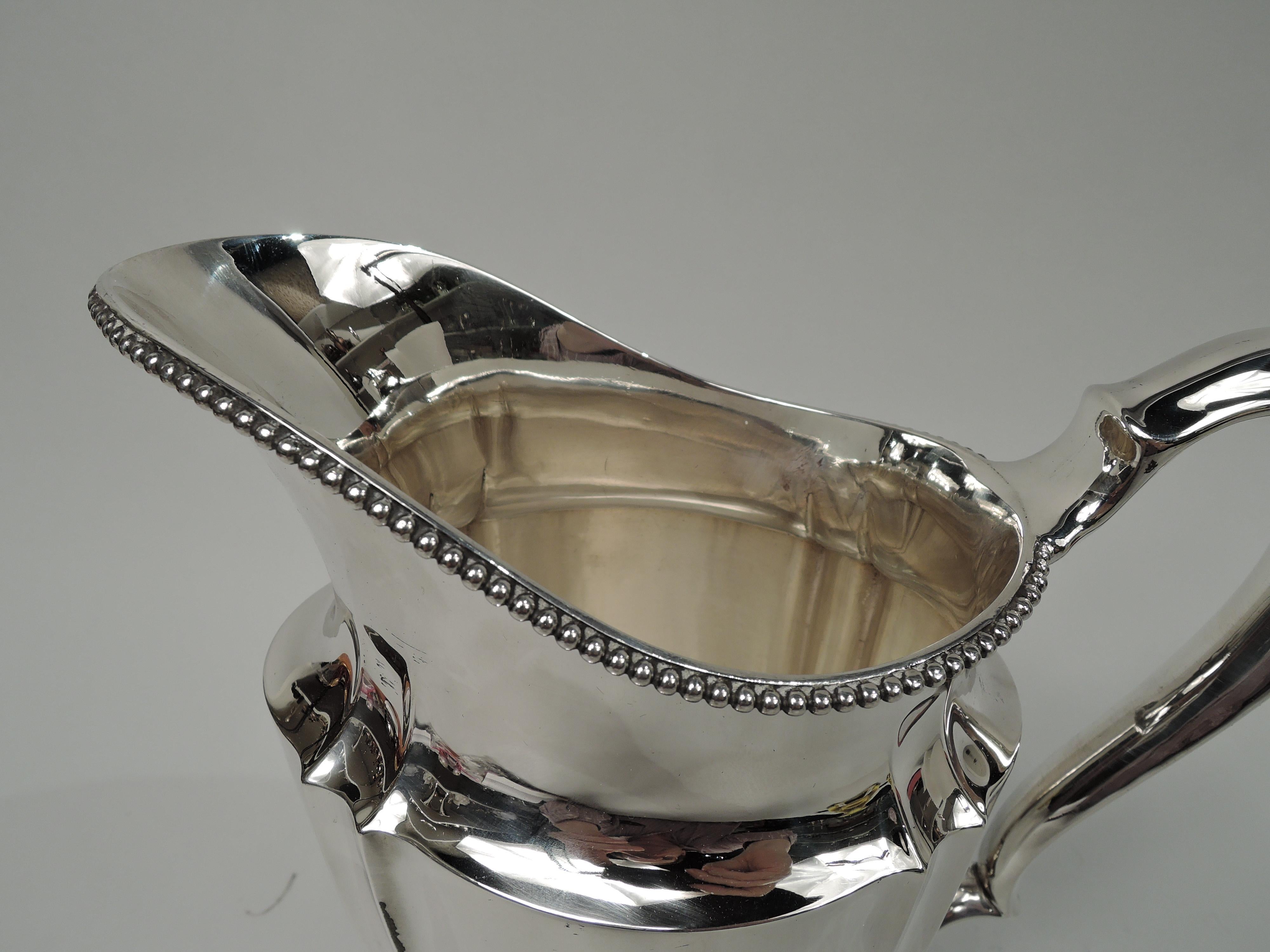 Victorian Classical sterling silver water pitcher. Made by Tiffany & Co. in New York. Tapering and fluted ovoid body, beaded helmet mouth, and high-looping double-scroll handle. Four cast leafing scroll supports. Fully marked including maker’s