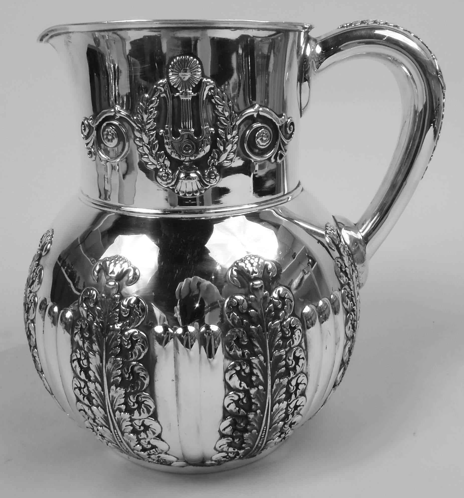 Victorian Classical sterling silver water pitcher. Made by Tiffany & Co. in New York, ca 1877. Globular bowl with drum-form neck, small lip spout, and c-scroll handle. Bowl has vertical ornament in form of applied acanthus leaves alternating with