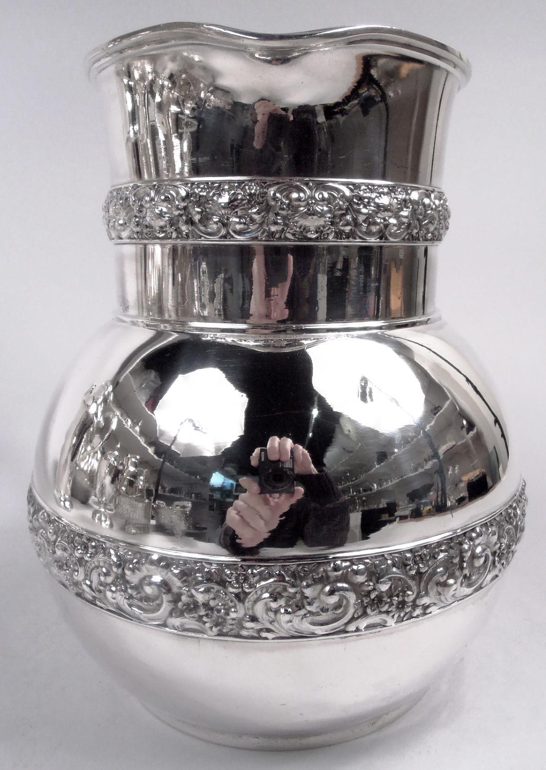 Jarra de agua clásica victoriana de plata de ley. Fabricado por Tiffany & Co. en Nueva York, hacia 1877. Cuenco globular, cuello en forma de tambor y pico con labio; asa en forma de c. El cuenco y el cuello tienen bandas de flores y volutas