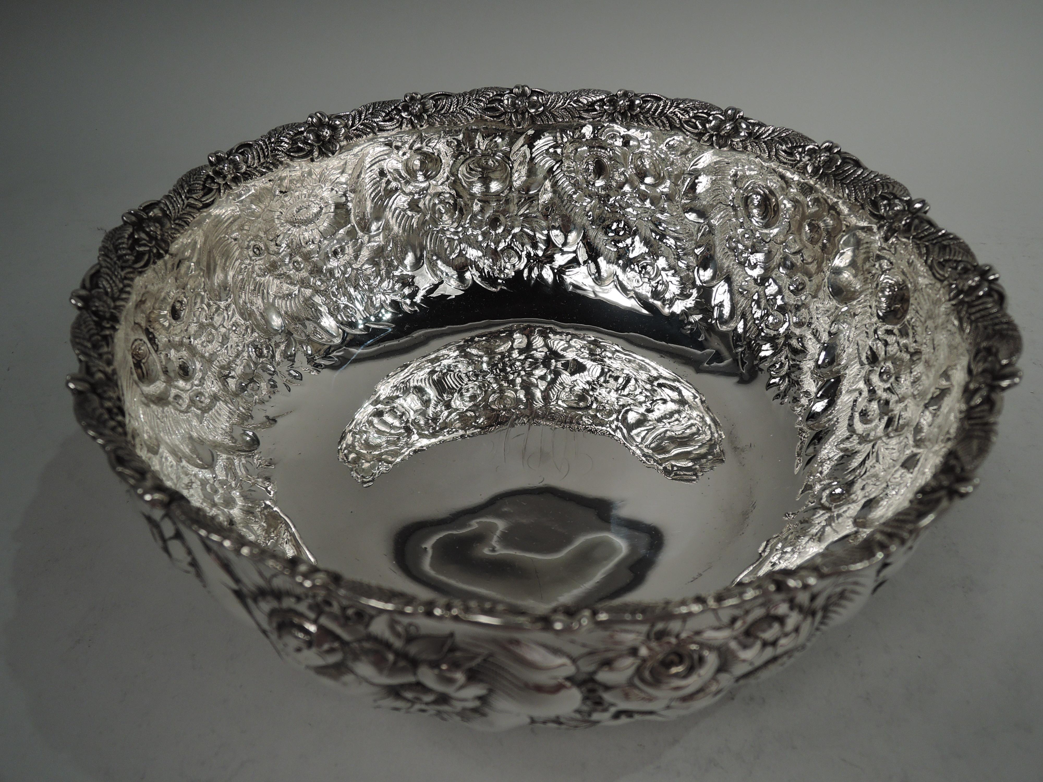 Victorian sterling silver bowl. Made by Tiffany & Co. in New York. Curved sides with repousse fern and flower pattern. Cast interior rim comprising alternating ferns and flower heads. Four leafing scroll-mounted paw supports. Fully marked including