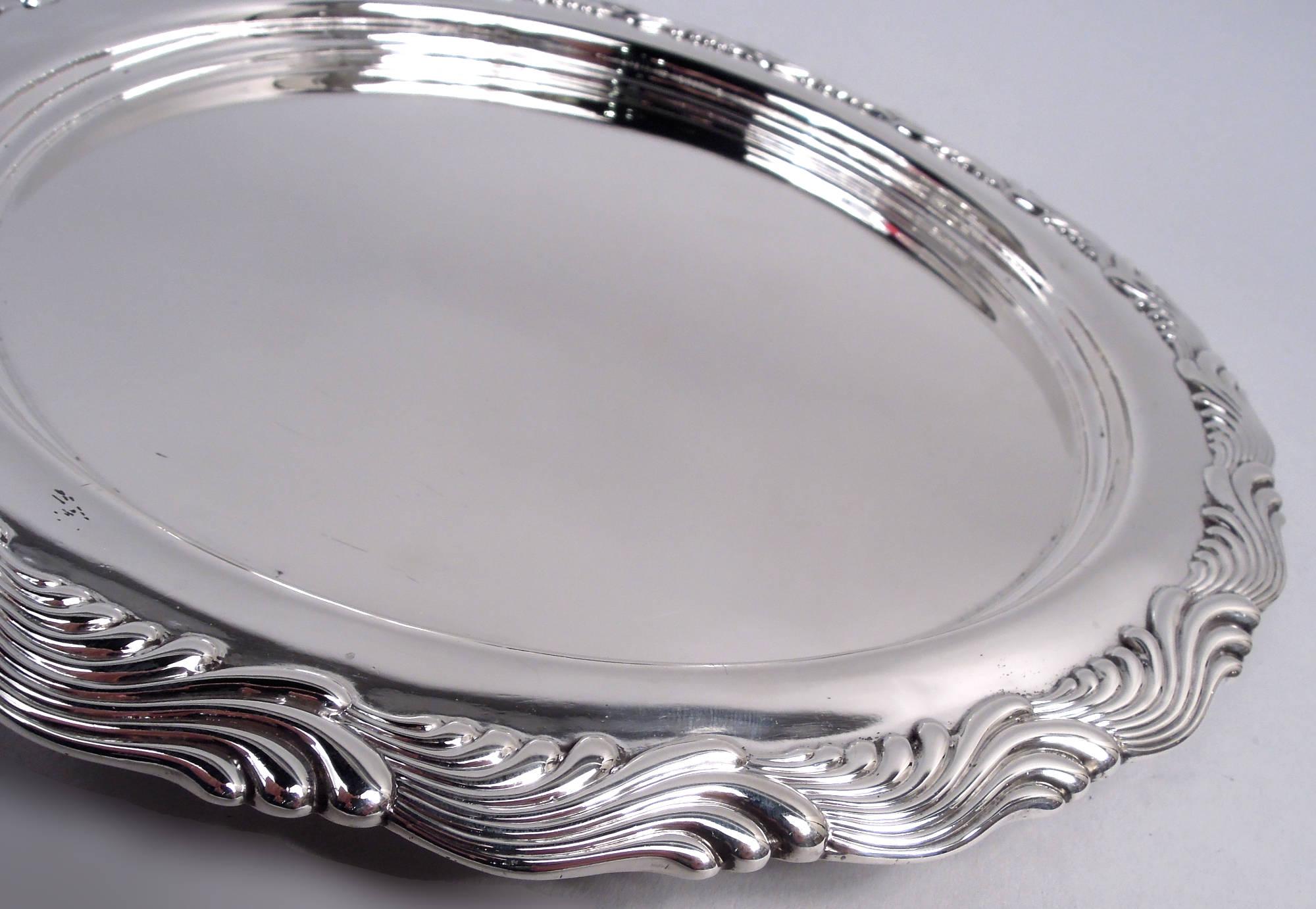 Plateau en argent sterling Wave Edge. Fabriqué par Tiffany & Co. à New York. Puits rond et profond ; épaule plate avec bord moulé comprenant des rinceaux ondulants qui se chevauchent. Entièrement marqué, y compris le cachet du fabricant, le numéro