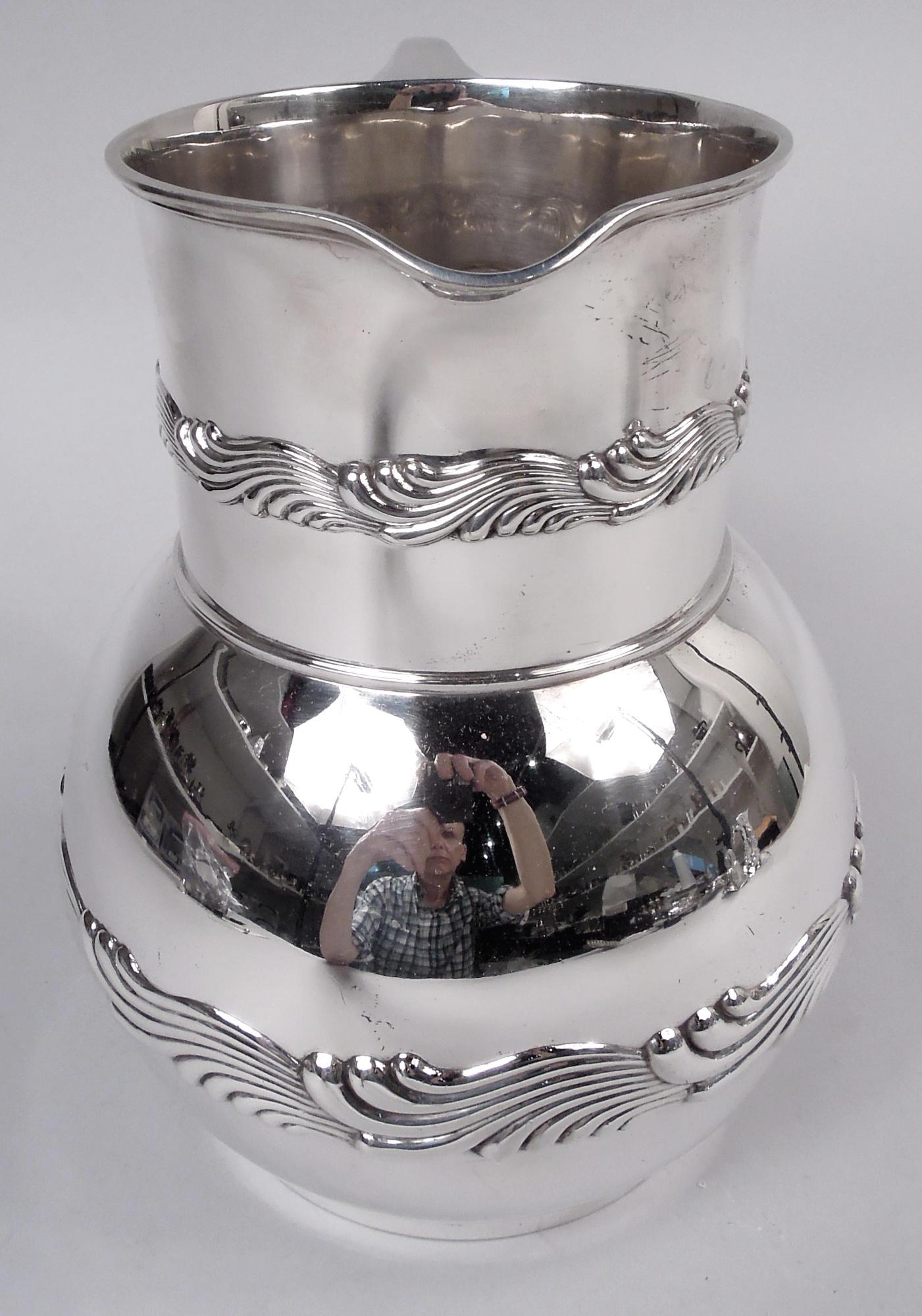 Wave Edge Wasserkrug aus Sterlingsilber. Hergestellt von Tiffany & Co. in New York, ca. 1885. Kugelförmige Schale mit trommelförmigem Hals, Ausguss mit kleiner Lippe und Henkel mit Schnörkel. Ziselierte Bänder mit sich überschneidenden Schriftrollen