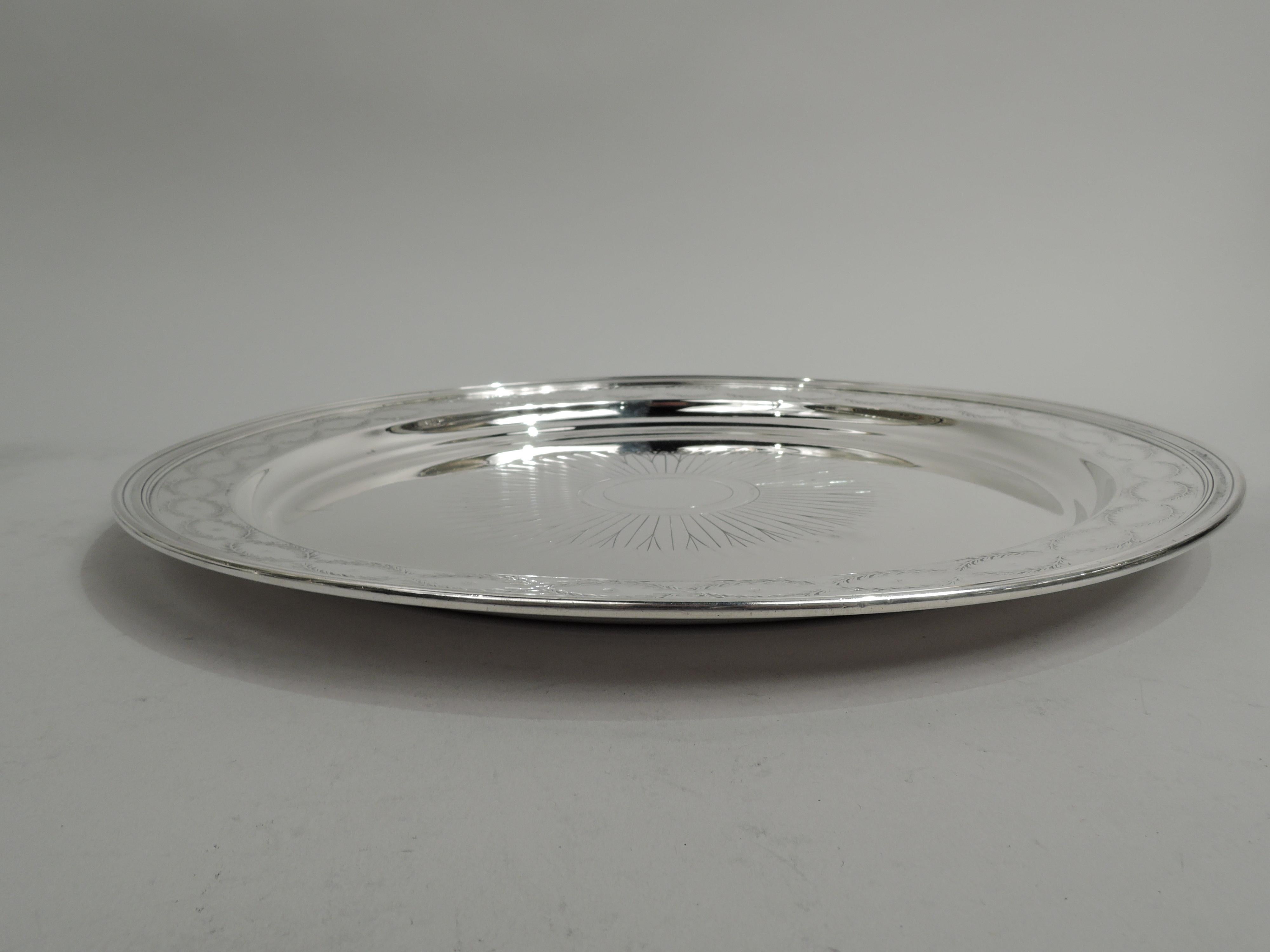 Winthrop sterling silver tray. Made by Tiffany & Co. in New York. Round well with patera comprising beaded rondel (vacant) radiating imbricated leaves. Shoulder flat and tapering with laurel wreaths inset with flower heads. A great piece in the