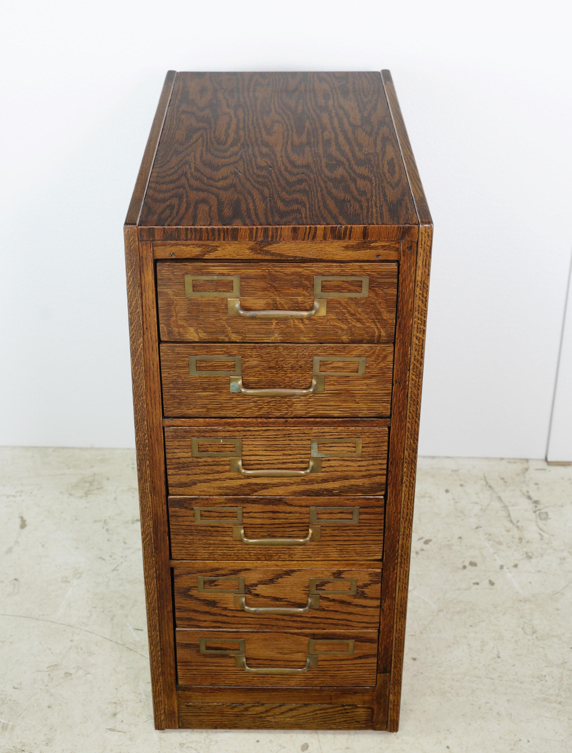 This antique tiger oak filing cabinet with six steel drawers and brass hardware is a rare gem from the past, combining the elegance of tiger oak grain with the durability of steel and timeless brass accents. This piece is unmarked. It is in great