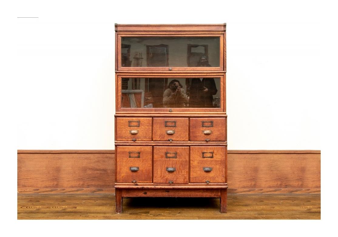 Antique tiger oak barrister bookcase with two glass doors above file drawers with brass cup hardware.
Non-slip compressors in each drawer. 

Dimensions: 39