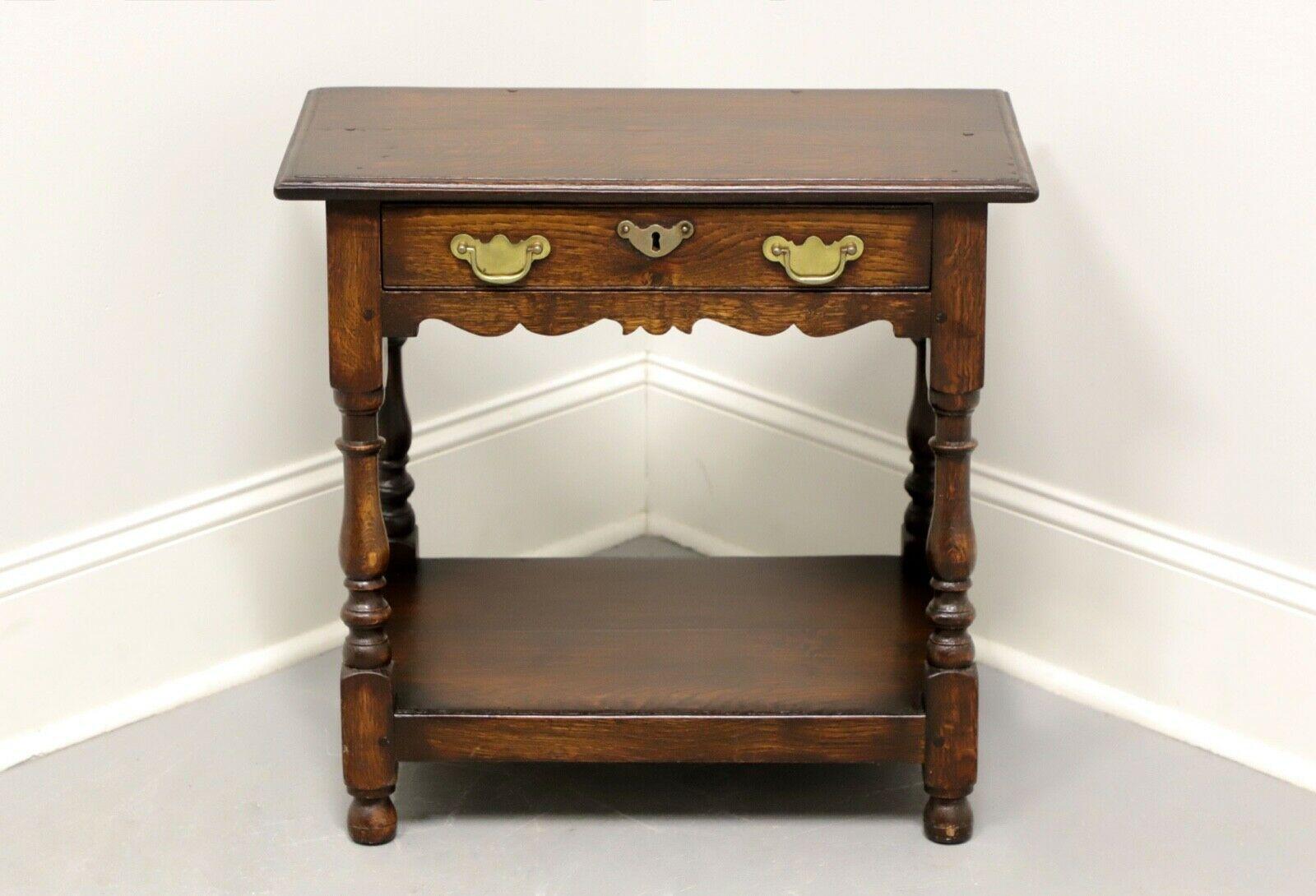 An antique Colonial style accent table, unbranded. Tiger oak with brass hardware. Features one dovetail drawer with lock (no key), lower shelf and turned legs. Possibly made in England or the USA, in the 19th Century.

Measures: 24.25 W 14.25 D