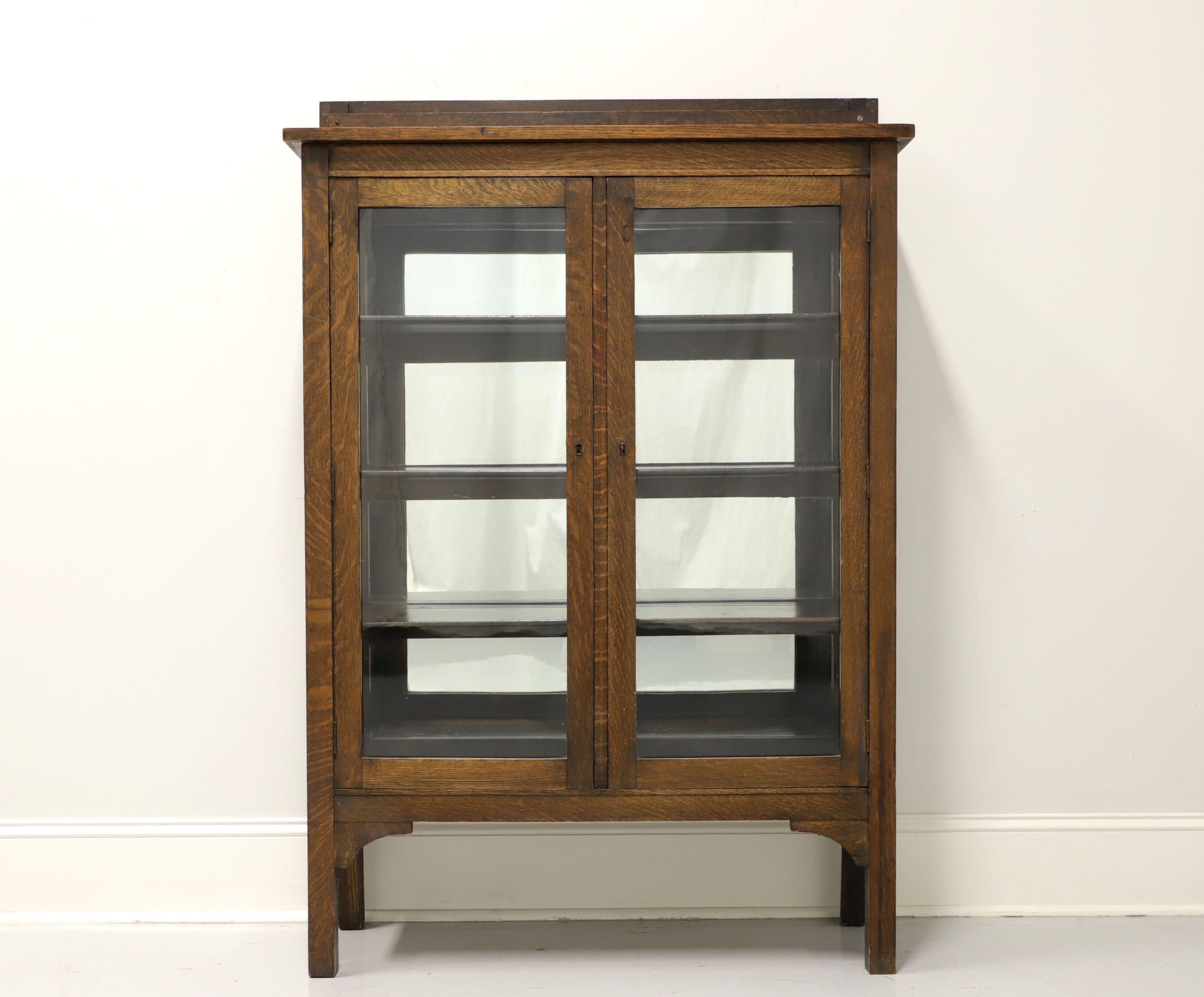 An antique Mission / Arts & Crafts style bookcase cabinet, unbranded. Solid tiger oak with magazine gallery on top, two lockable glass doors, glass side panels and straight legs. Features three adjustable plate grooved shelves. Includes one key.