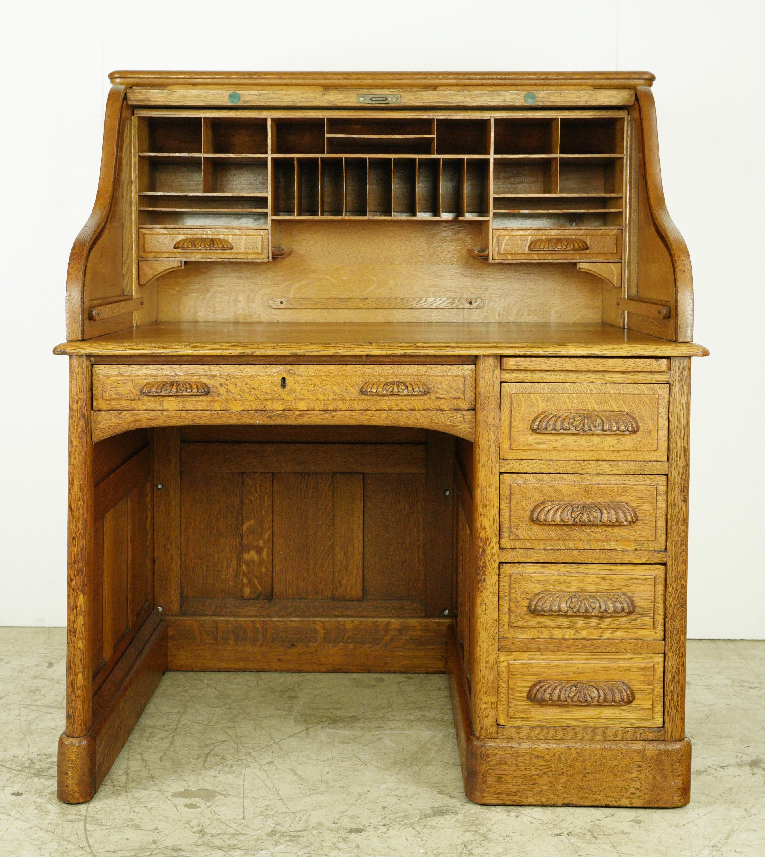 Medium tone tiger oak roll top desk with drawers on the right side that lock simultaneously to the top and three secret drawers. The roll top locks automatically when closed. Some visible screws on the inner leg area. Some scratches and dings. This