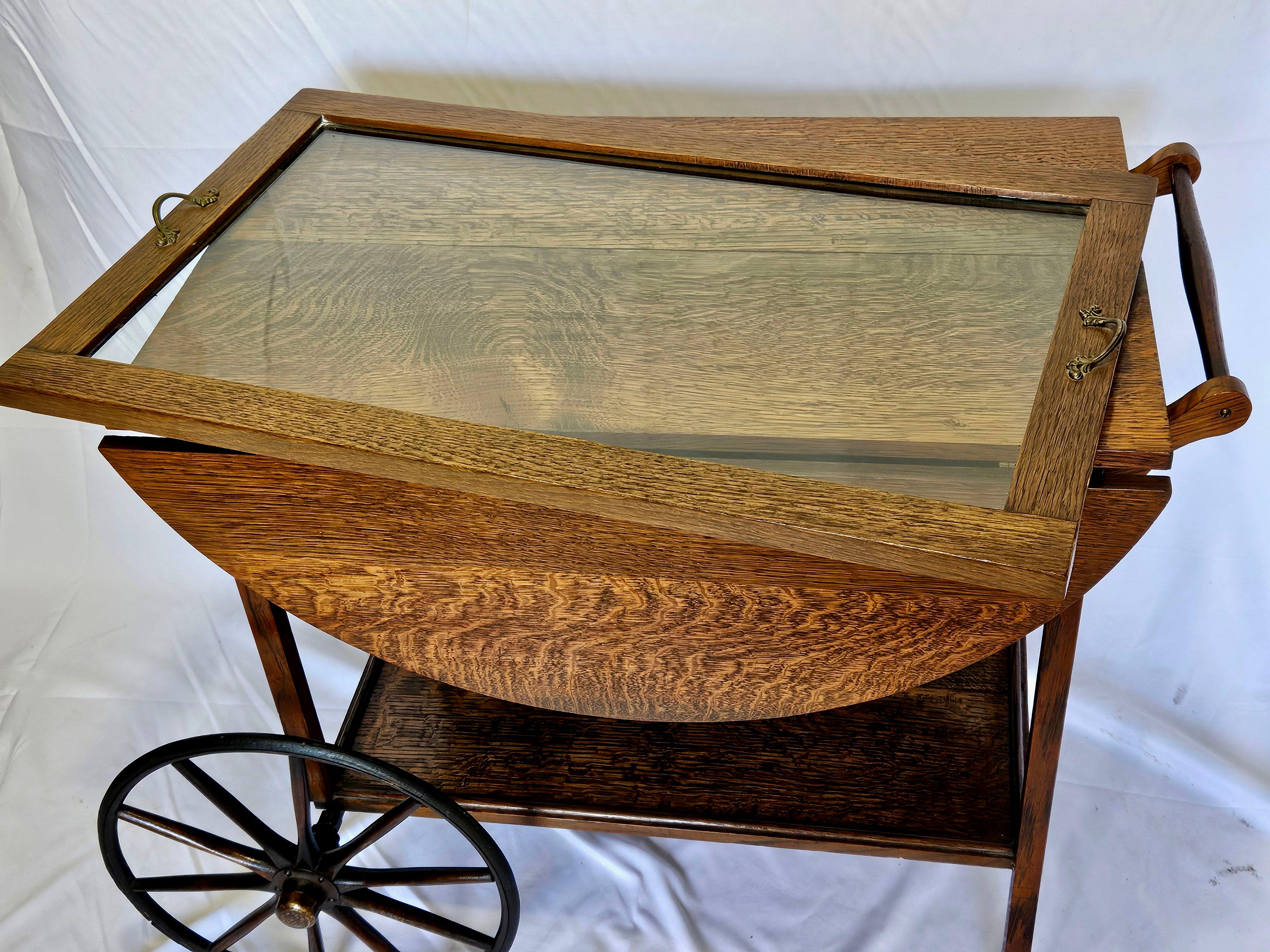 We are pleased to offer this beautiful Regency-style Tiger Oak Tea Cart, from the late 19th to the early 20th century.
Made of Oak with unique tiger patterns throughout with a removable glass tray top, and the original brass handles, on a convenient