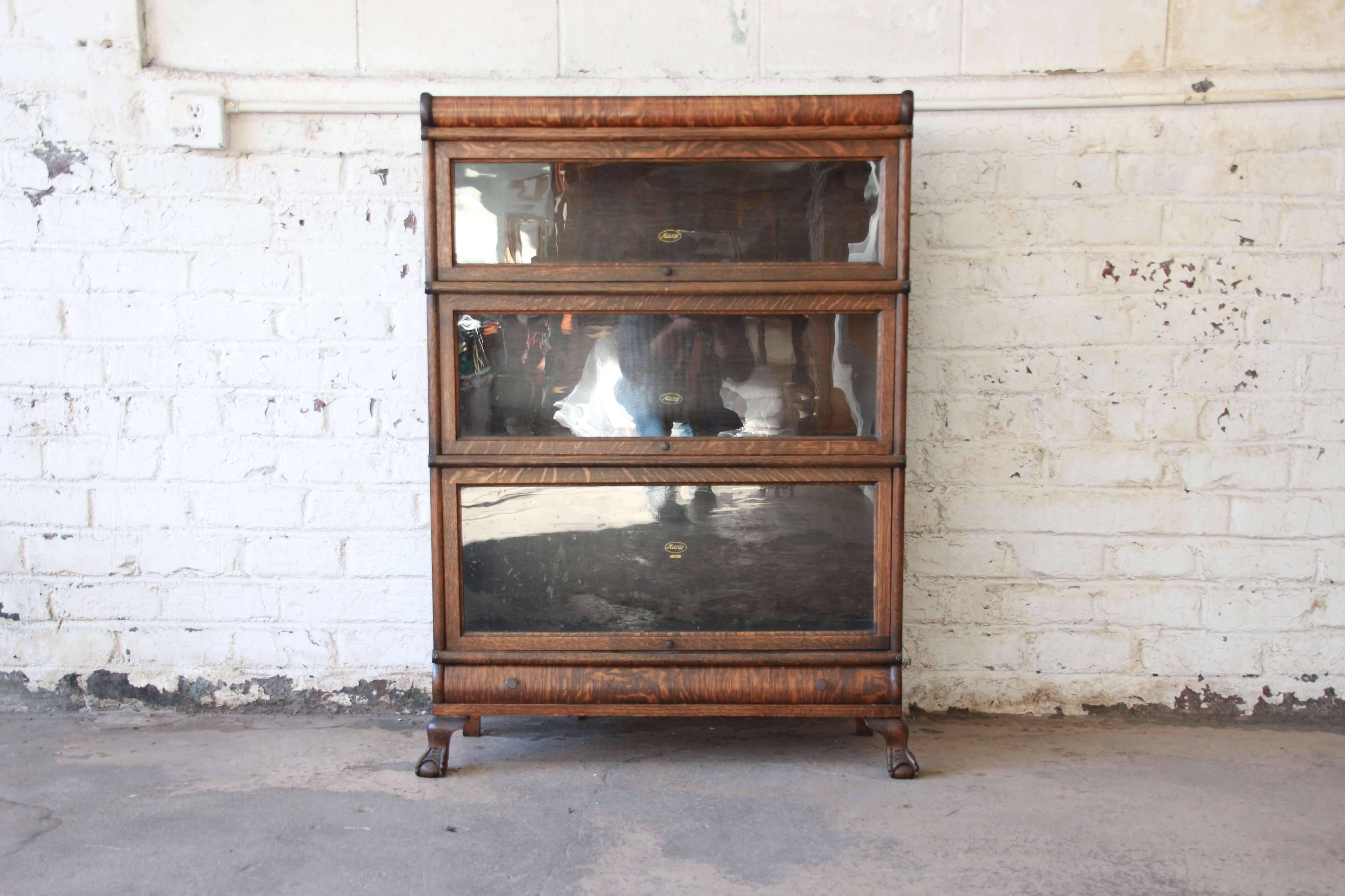 Offering a very nice tiger oak three stack barrister bookcase by Macey. The bookcase has a beautiful tiger oak finish. Each glass front door opens and closed smoothly and has plenty of room for storage. Near the bottom of the piece is a drawer for