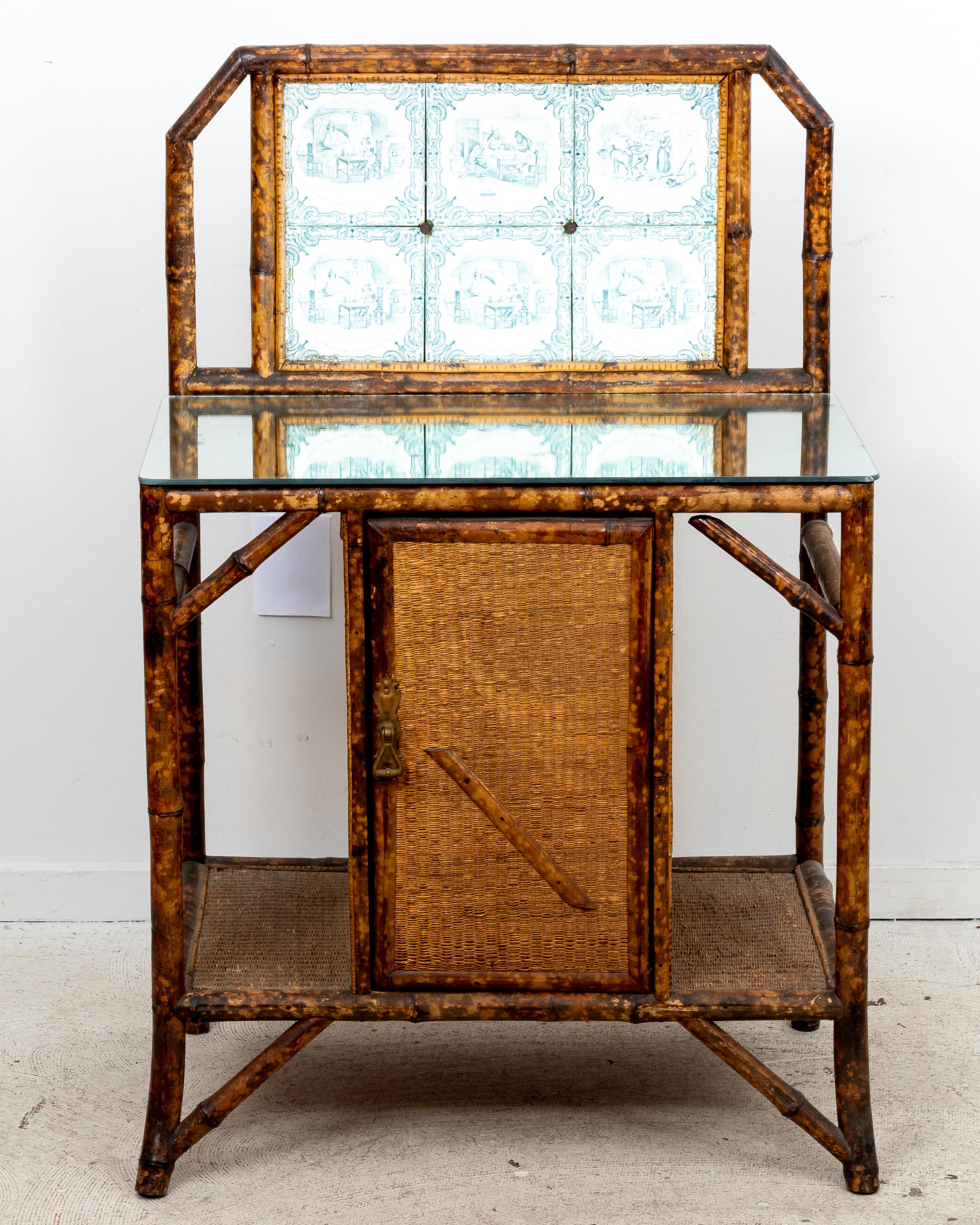 Circa late 19th to early 20th century antique bamboo hall stand featuring painted tile back and distressed, mirrored top. Single cabinet door below. Good overall, original condition. Please note of wear consistent with age. Mirror is probably not