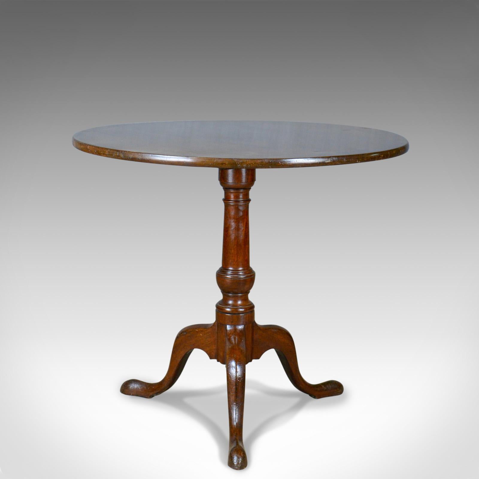 This is an antique tilt-top table, an English, mahogany side table dating to the early 19th century, circa 1800.

Appealing patina and grain interest in the mahogany
Good color depth shining through the wax polished finish
Modest proportions