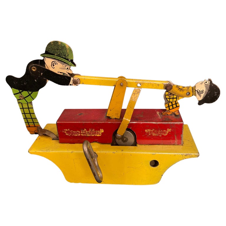  This cute little toy was made at the height of the character collectible toys, the 1930's. Lithographed on tin are the images of the famous comic strip characters, Mutt & Jeff. Just wind it up, lift up the lever, and the wheels start spinning. Can