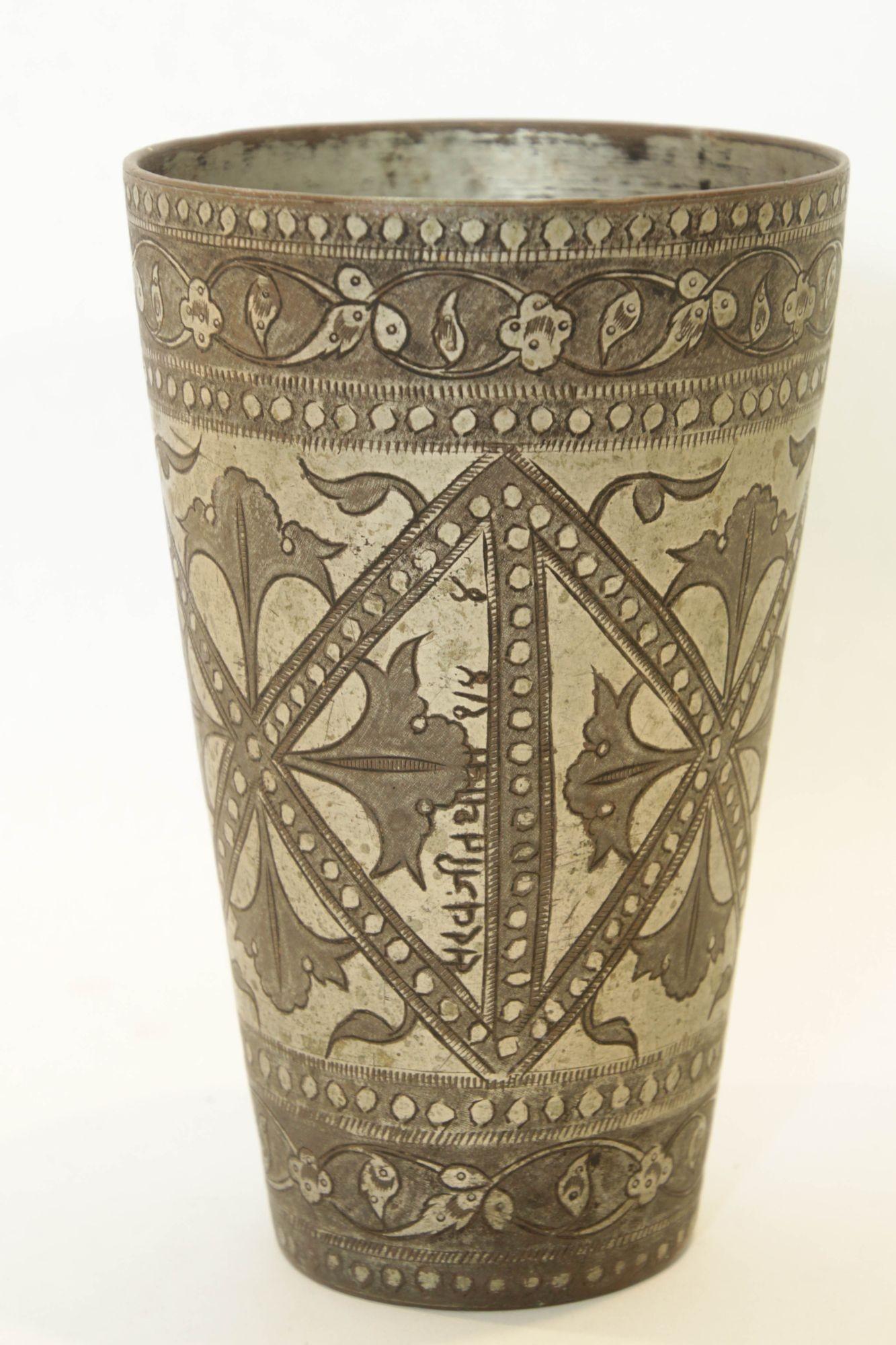 Vaso antiguo de cobre estañado plateado martillado y grabado a mano, de estilo mogol, bellamente cincelado a mano y decorado con motivos geométricos y botánicos.
Taza de metal para beber lassi de estilo mogol islámico, única en su género, procedente