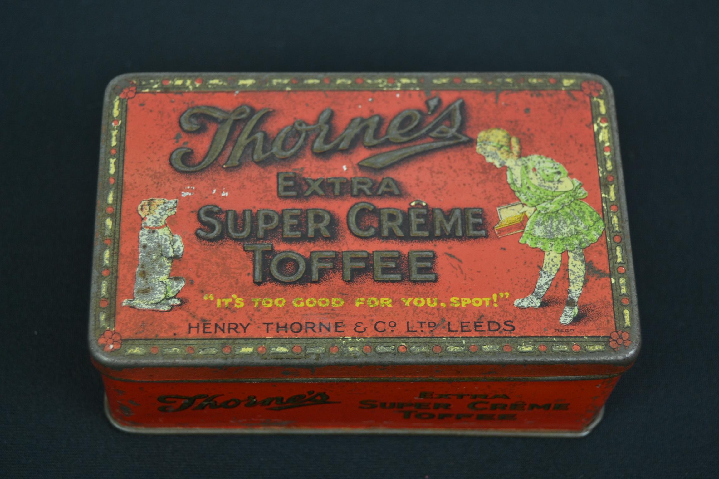 Antique confectionary tin for toffees by Henry Thorne and co, Leeds , England.
A cute small red lithographic tin with a girl and dog and also embossed lettering on the lid. 
A storage tin for extra super Crême toffees. This antique toffee tin or