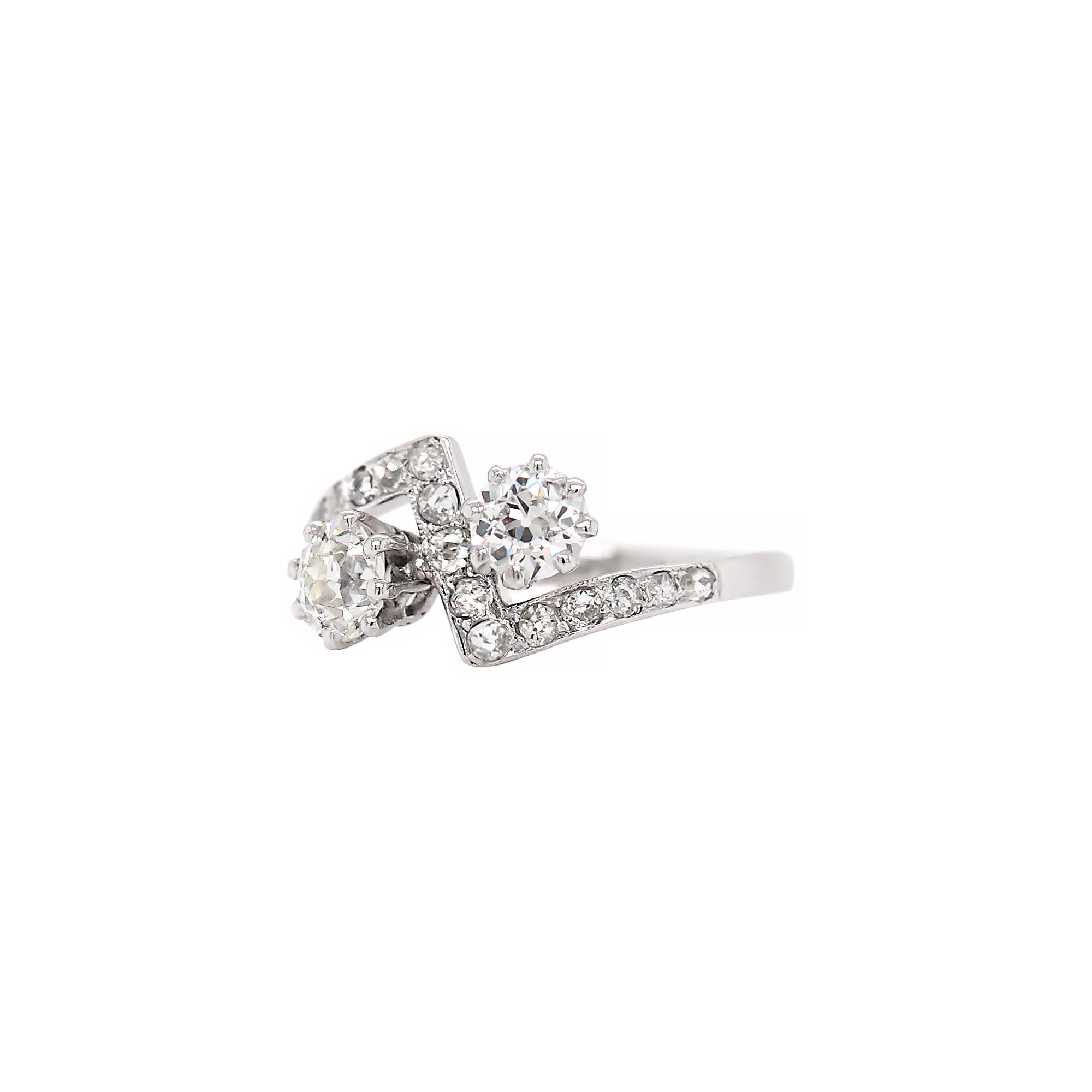 This one of a kind Art Deco engagement ring features two old cut diamonds with a combined weight of 0.96ct both set in eight claw open back settings. These beautiful stones are mounted in a crossover zig zag mount, pavé set with 15 old cut diamonds