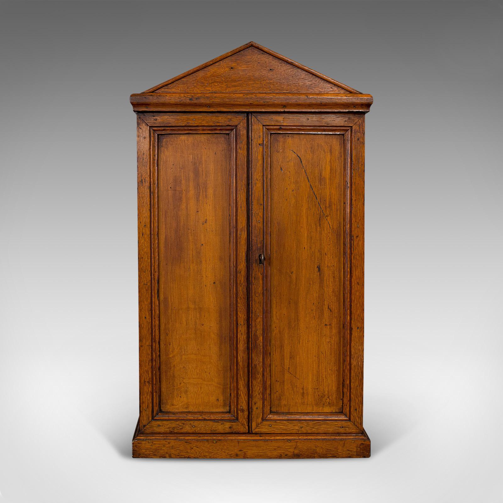 This is an antique tool cupboard. An English, oak wall hanging cabinet by the Army and Navy Co-operative, dating to the Edwardian period, circa 1910.

Fascinating tool cabinet with elegant craftsmanship
Displays a desirable aged patina
Select