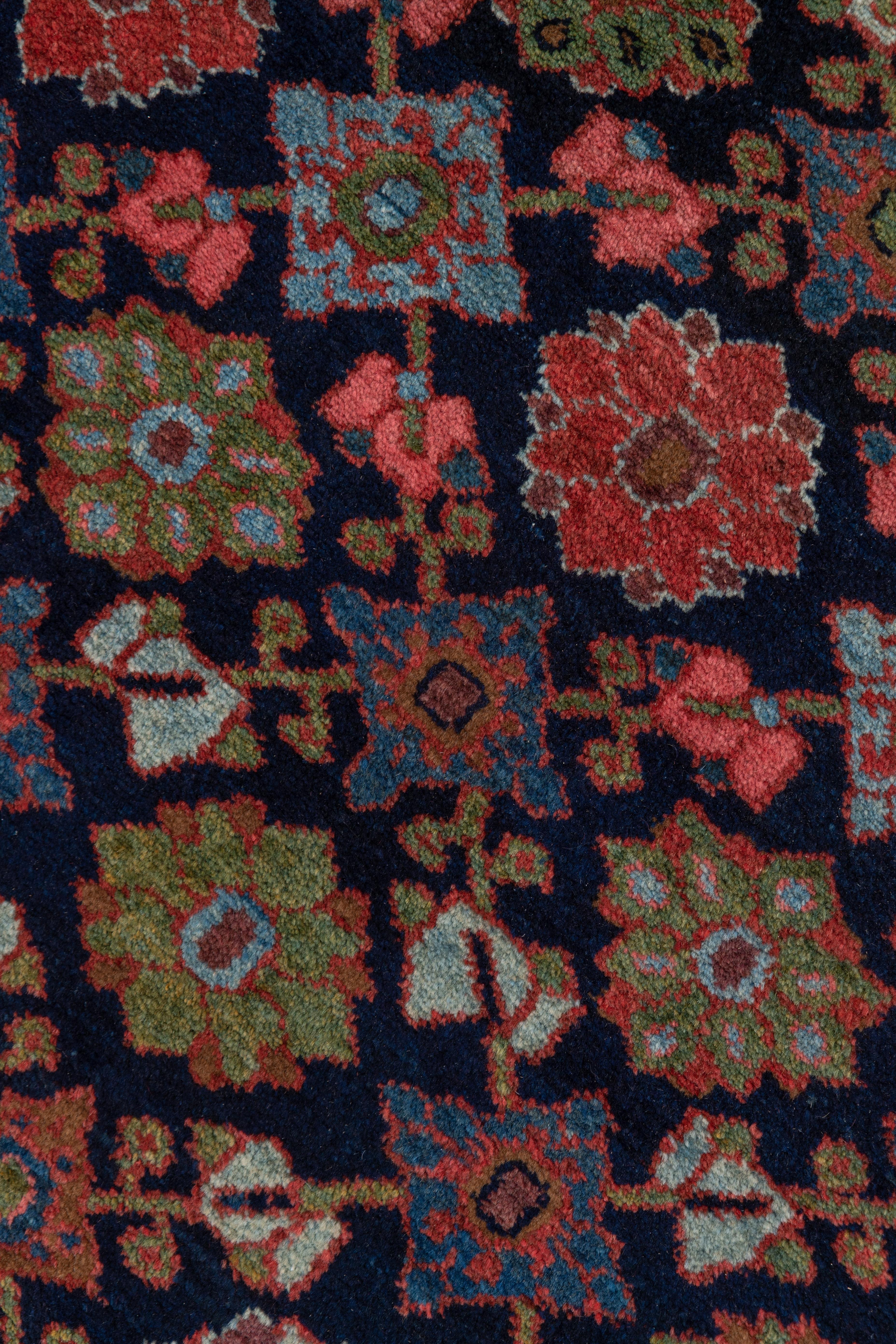 This top condition west Persian rustic runner has a navy field with a formal, geometric version of the Mina Khani rosette trellis design detailed in medium blue, light blue, rose , ecru and green. The main border shows an angular vine and fish bone