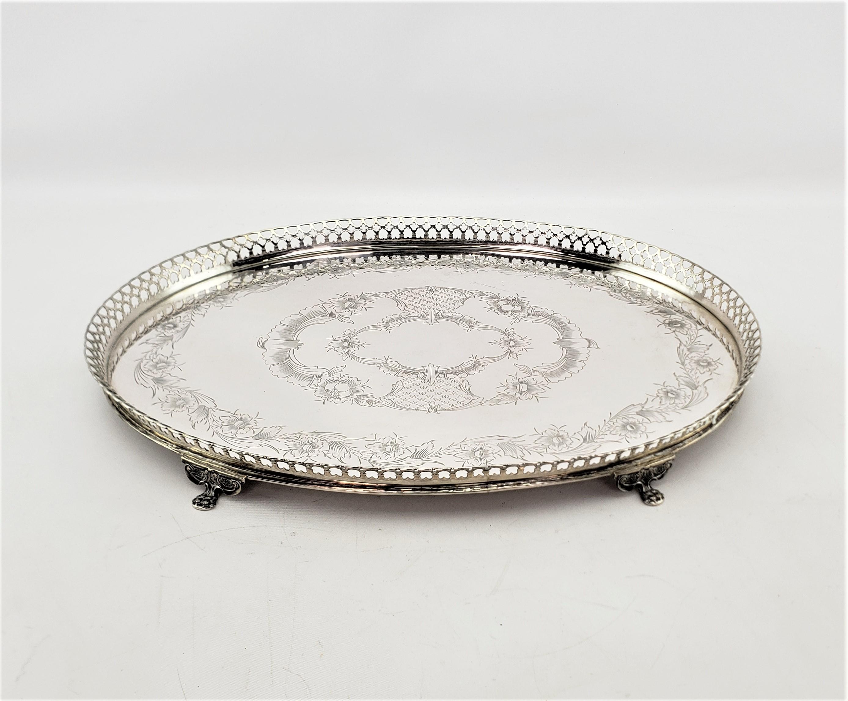 This antique oval serving tray was made by Topazio of Portugal in approximately 1900 in a Victorian style. The tray is composed of .833 silver and has a pierced gallery and ornate floral engraving on the top of the tray. The tray stands on four