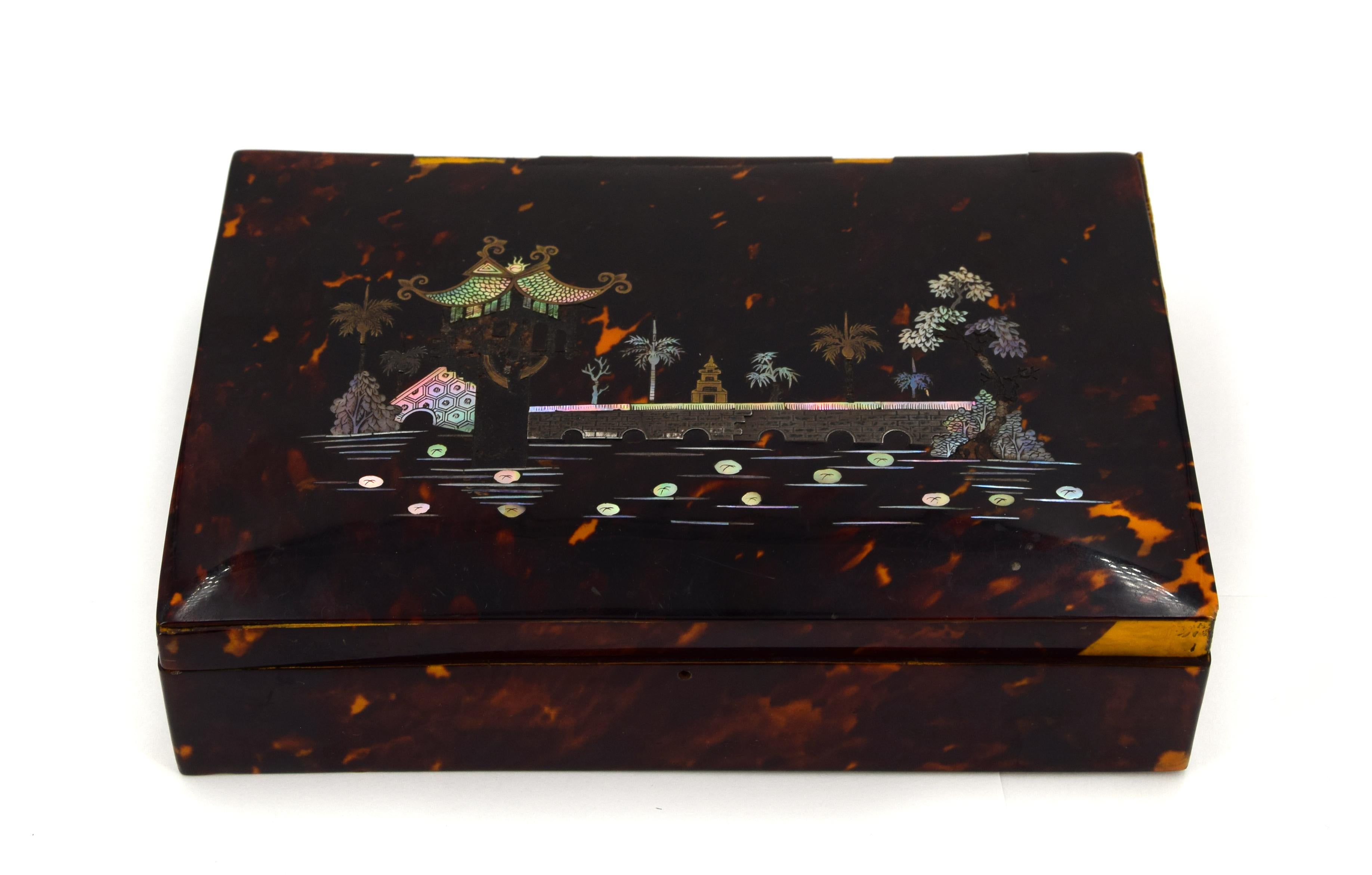 Antique tortoiseshell wooden box with oriental decoration, maybe a Chinese landscape, on the cover. 

This artwork is shipped from Italy. Under existing legislation, any artwork in Italy created over 70 years ago by an artist who has died requires