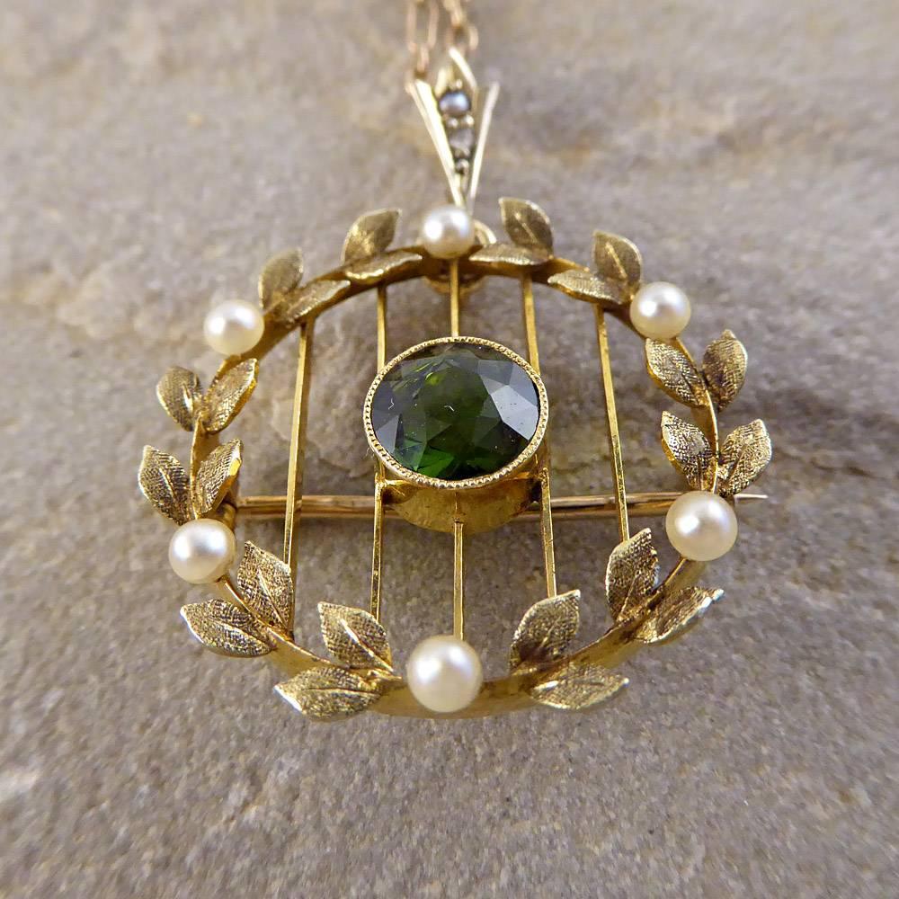 This Pretty Edwardian Leaf Pendant / Brooch features an alluring Tourmaline stone surrounded by Six Pearls. It is Crafted in 15ct Gold and is hung on a Period 9ct Gold Chain. This Darling piece is both Classic and Graceful, designed to beautify the