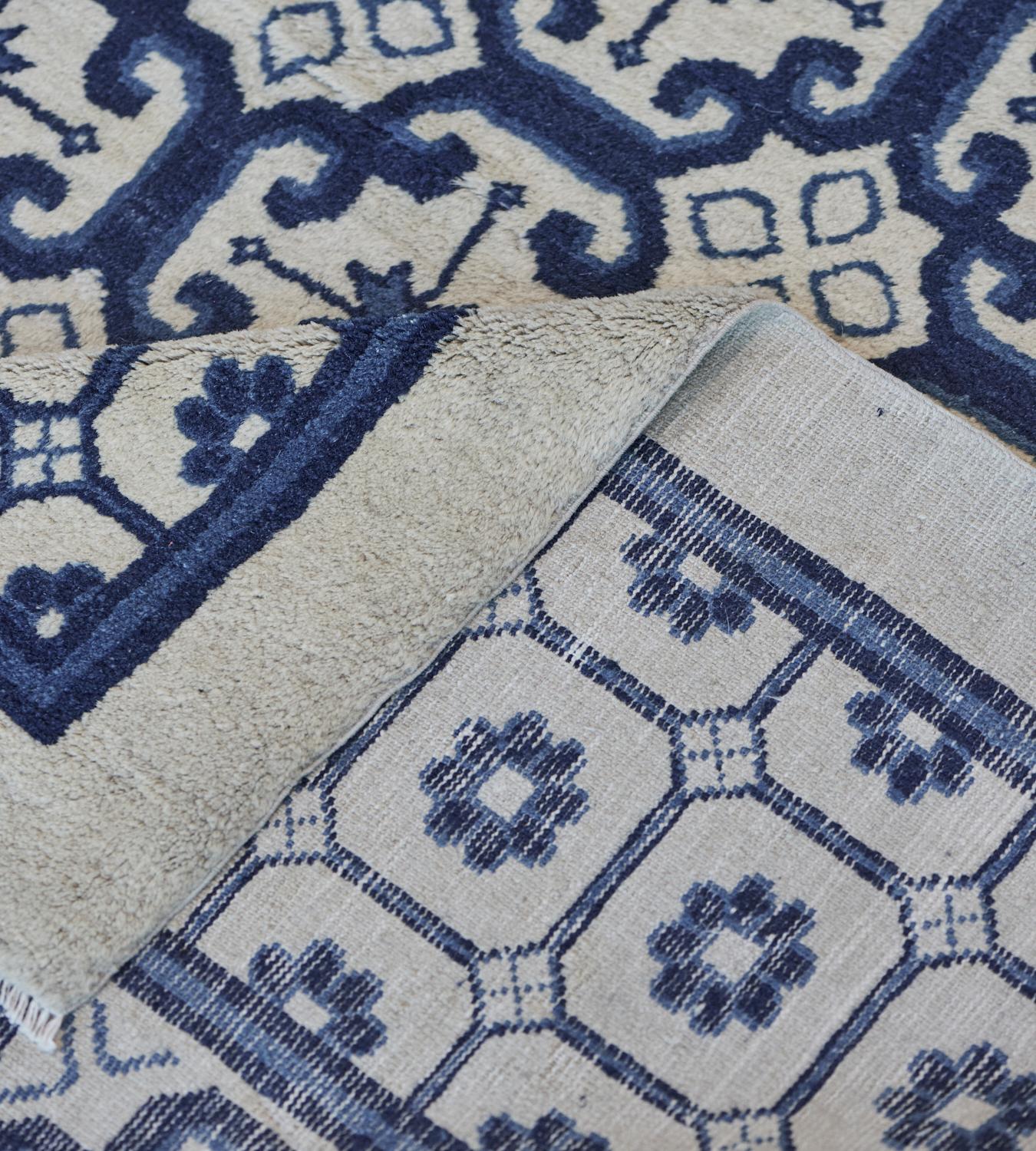 This antique, circa 1900, Chinese Peking rug features a field with an overall design of vertical rows of indigo-blue stepped lozenges each containing an ivory panel with a central light blue stellar flowerhead alternating with rows of ivory stellar