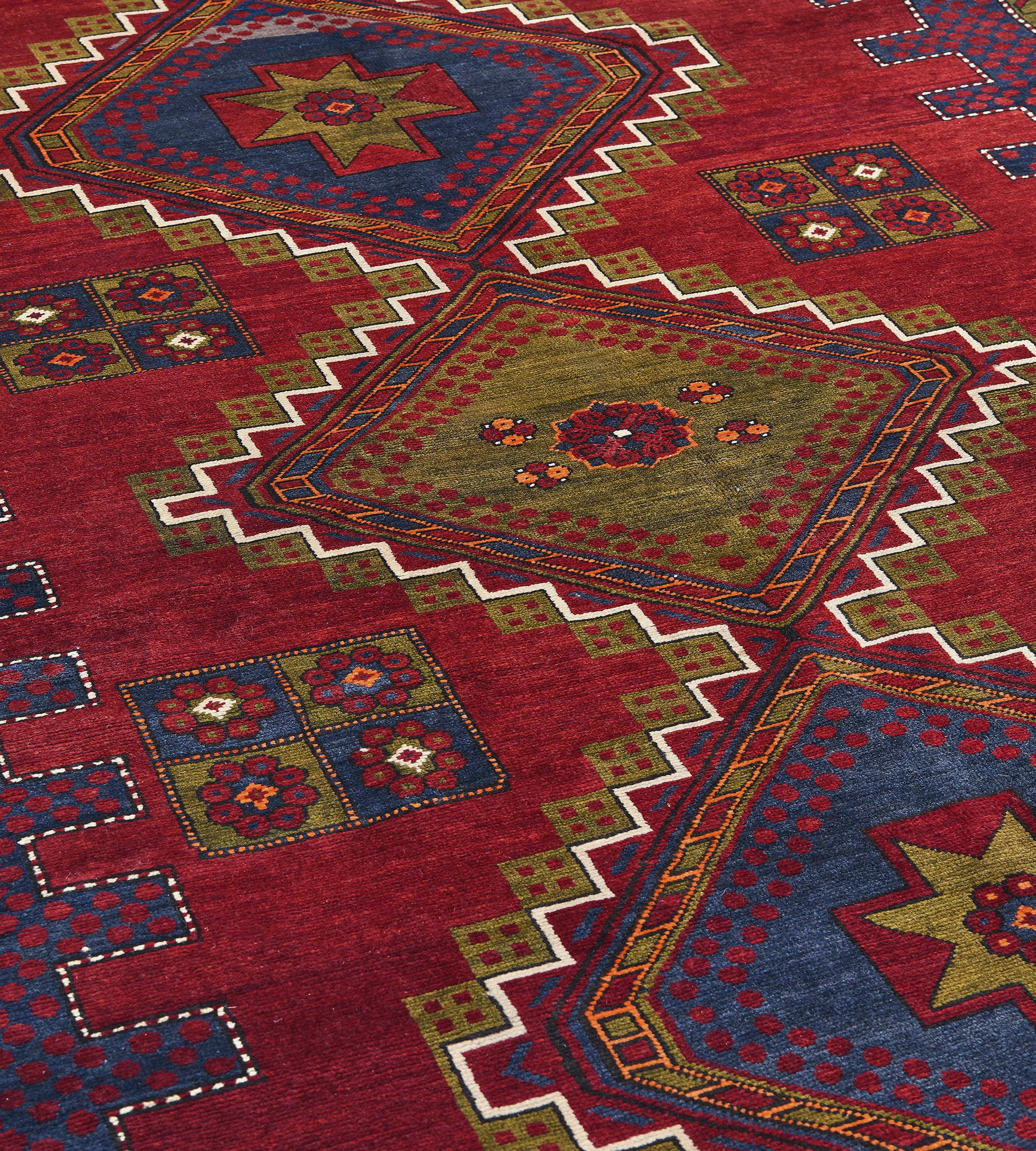 This traditional handwoven Caucasian Shirvan rug has an attractive shaded ruby field counterposed with sparse delicate flowerhead motif, enclosing complementary stepped indigo and chartreuse triple medallions, in unusual polychrome striped and polka