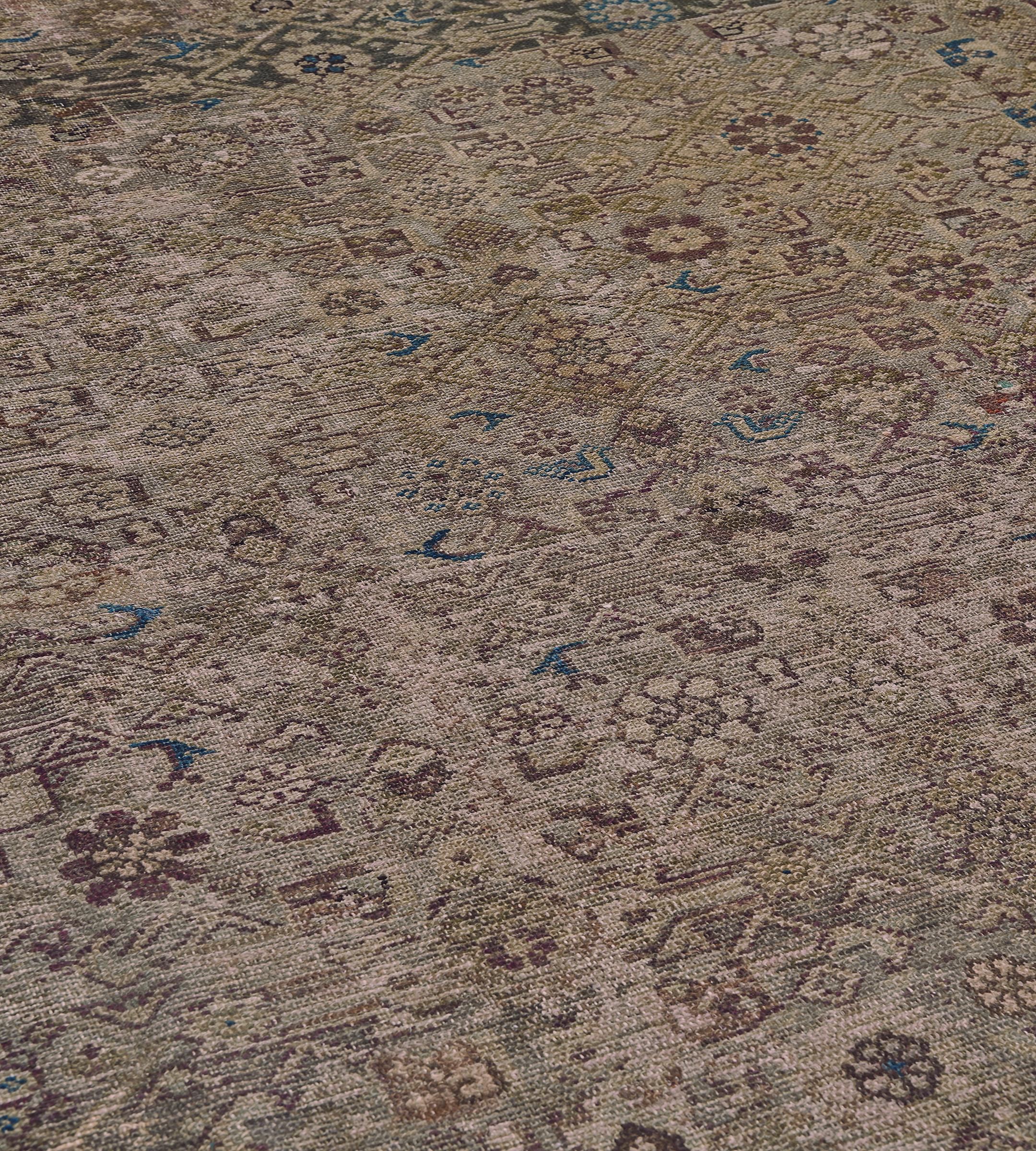 Dieser traditionelle handgewebte persische Fereghan-Teppich hat ein schattiertes khakifarbenes Feld mit einem Herati-Muster in einer beigefarbenen, lockeren Blumenrankenbordüre zwischen einer Fülle von detaillierten floralen und geometrischen