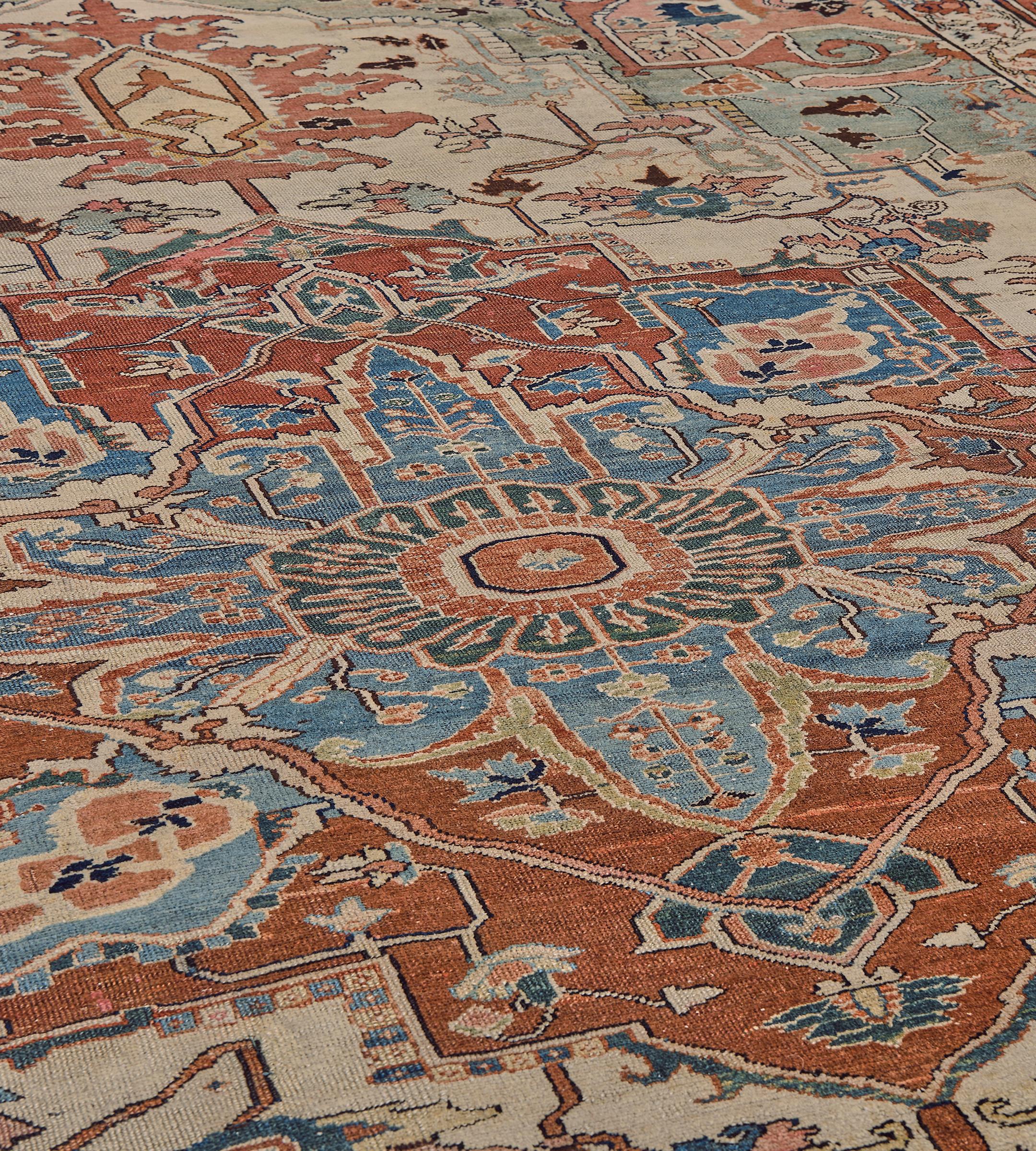 This traditional hand-woven Persian Serapi rug has an inviting beige field of dense angled palmette vines, enclosing a regal rust medallion with central bold radiating rosette, with pistachio spandrels of similar motif, in a shaded rust turtle