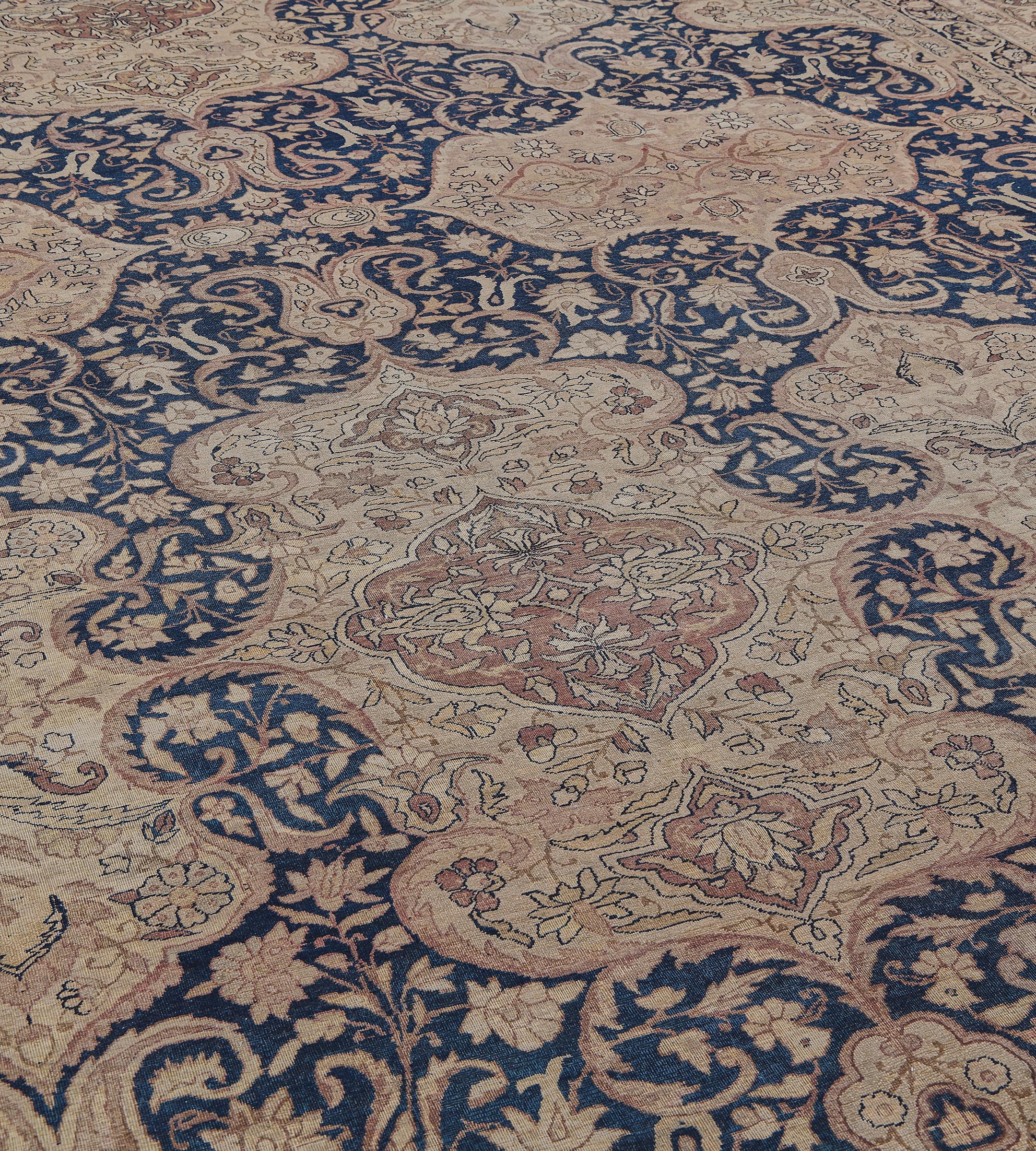 Ce tapis persan traditionnel tissé à la main est composé d'un champ indigo foncé nuancé avec un enroulement de fleurs et de palmettes autour d'une paire de cartouches horizontaux marron clair reliés à chaque extrémité et de trois cartouches