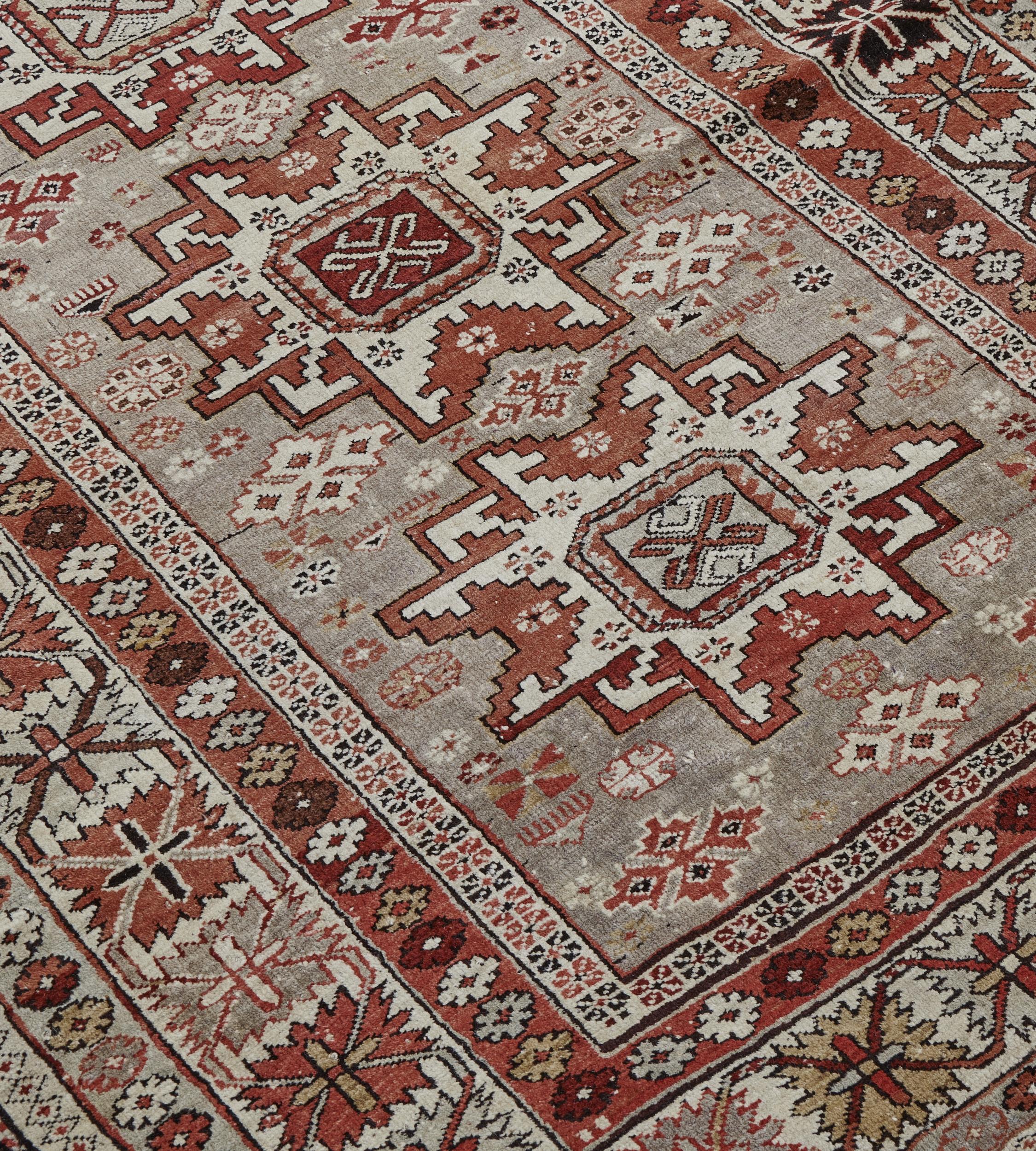 This traditional hand-woven Caucasian Shirvan rug has a gray pistachio field with stepped geometric motif enclosing a central column of stylized stepped lozenge medallions, in an ivory geometric border, between several geometric and floral stripes.