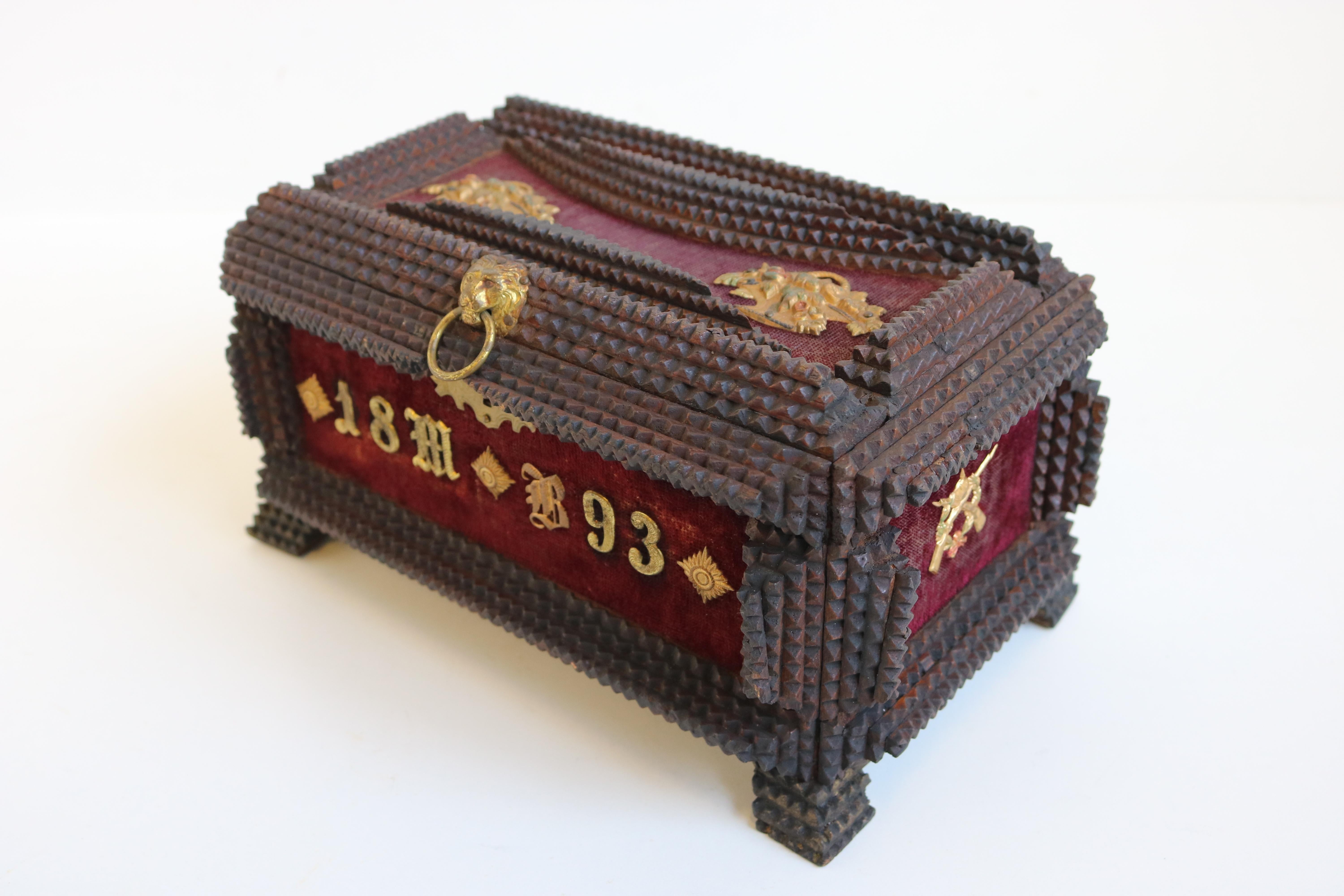 Magnifique boîte Tramp Art / Boîte à bijoux marquée 1893 et décorée de laiton. 
La boîte contient plusieurs fusils et casques de brochet et une tête de lion tenant un anneau en laiton pour ouvrir le coffre. 
Ce coffre a probablement été fabriqué