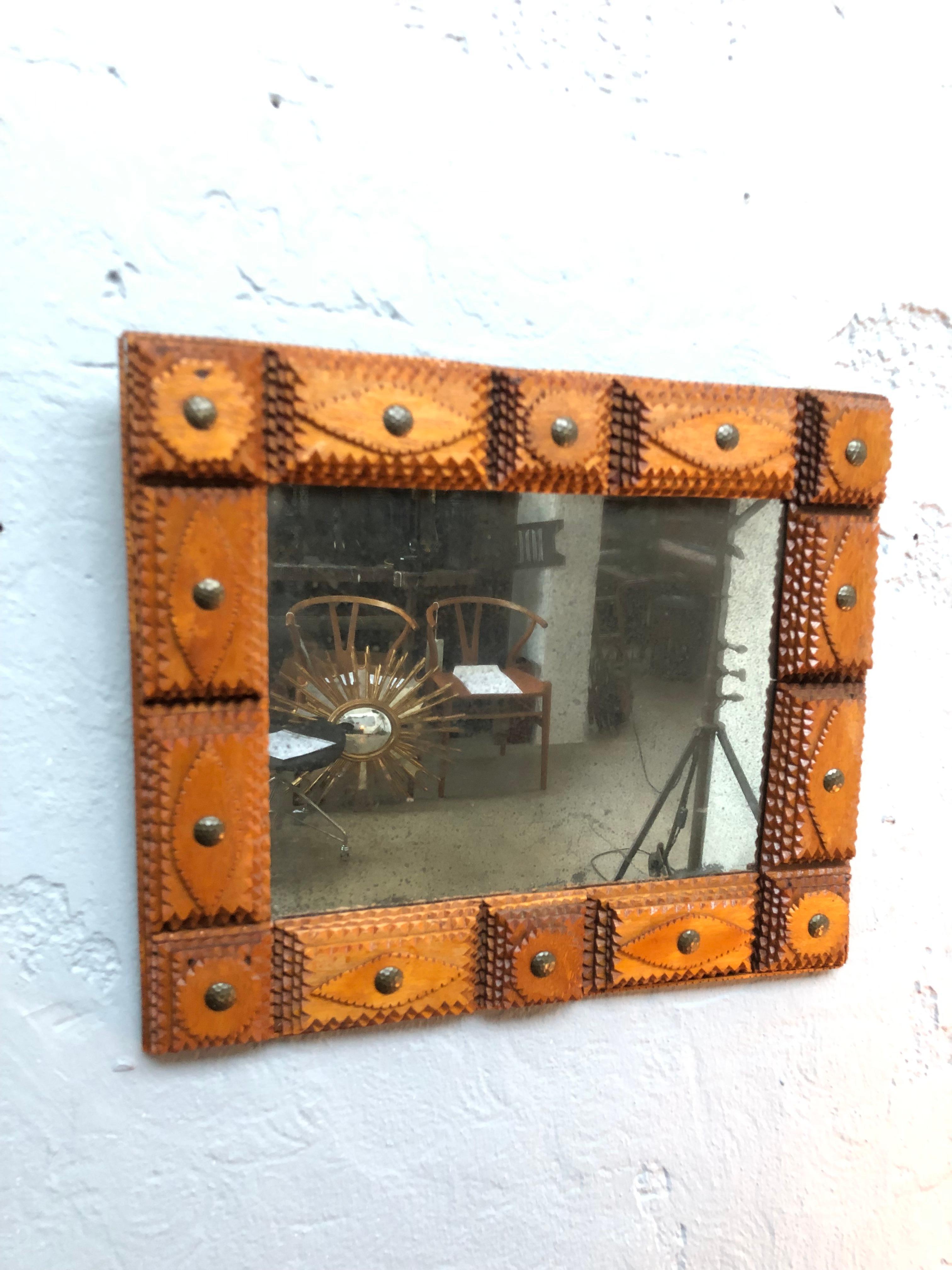 Antique tramp art wall mirror. 
Made from cigar boxes. 
With 4 layers of carved teak wood. 
Also with large brass tacks. 
A lovely patina to the glass mirror plate and also the wood and brass. 
A lovely decorative item that would grace any hallway