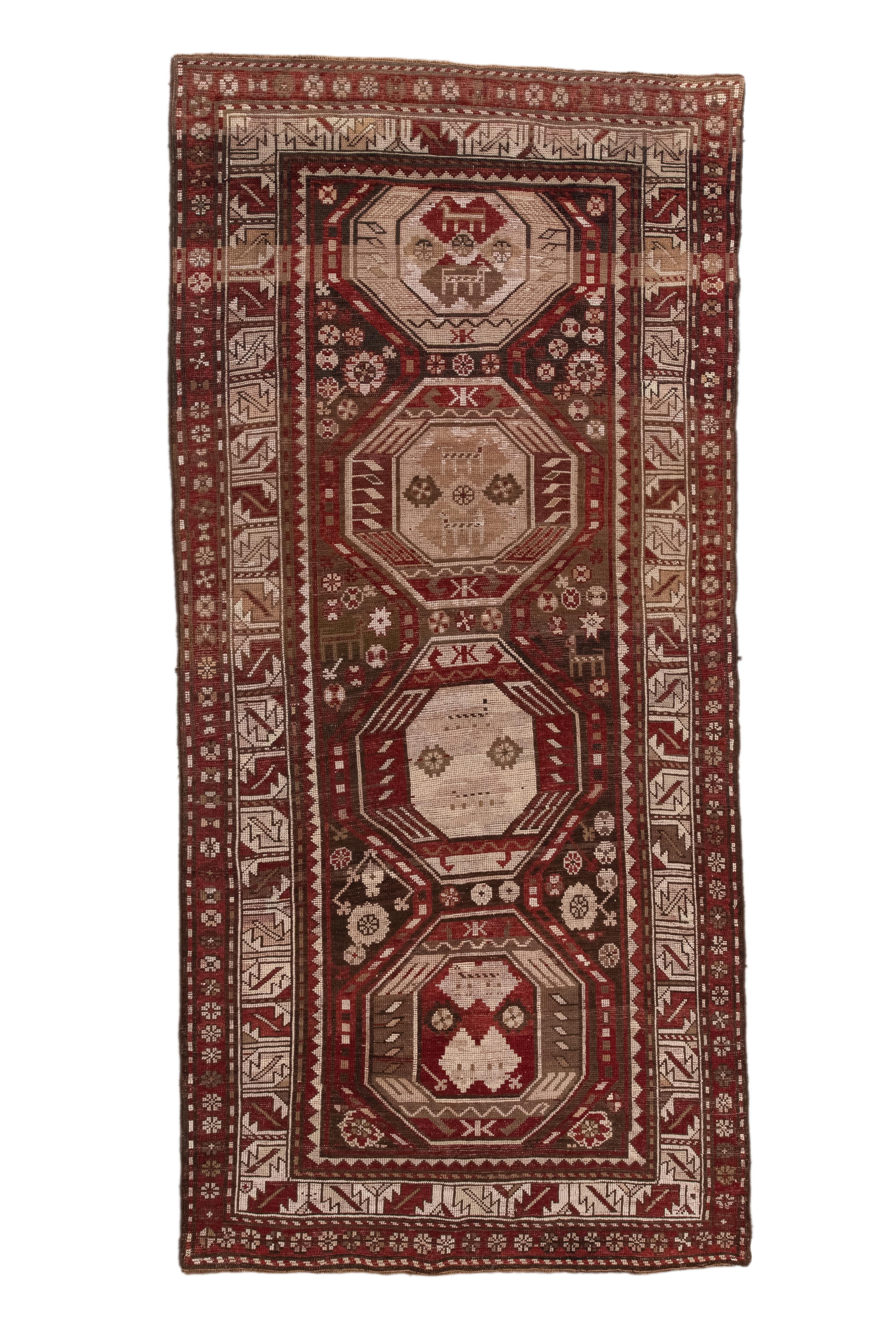 Transcaucasian Long Rug
Caucasus/Northwest Persia

The darkly saturated red field displays a column of four slightly irregular, layered octagons in brown and beige tones. Pairs of animals decorate these elements. Animals, rosettes and stars support