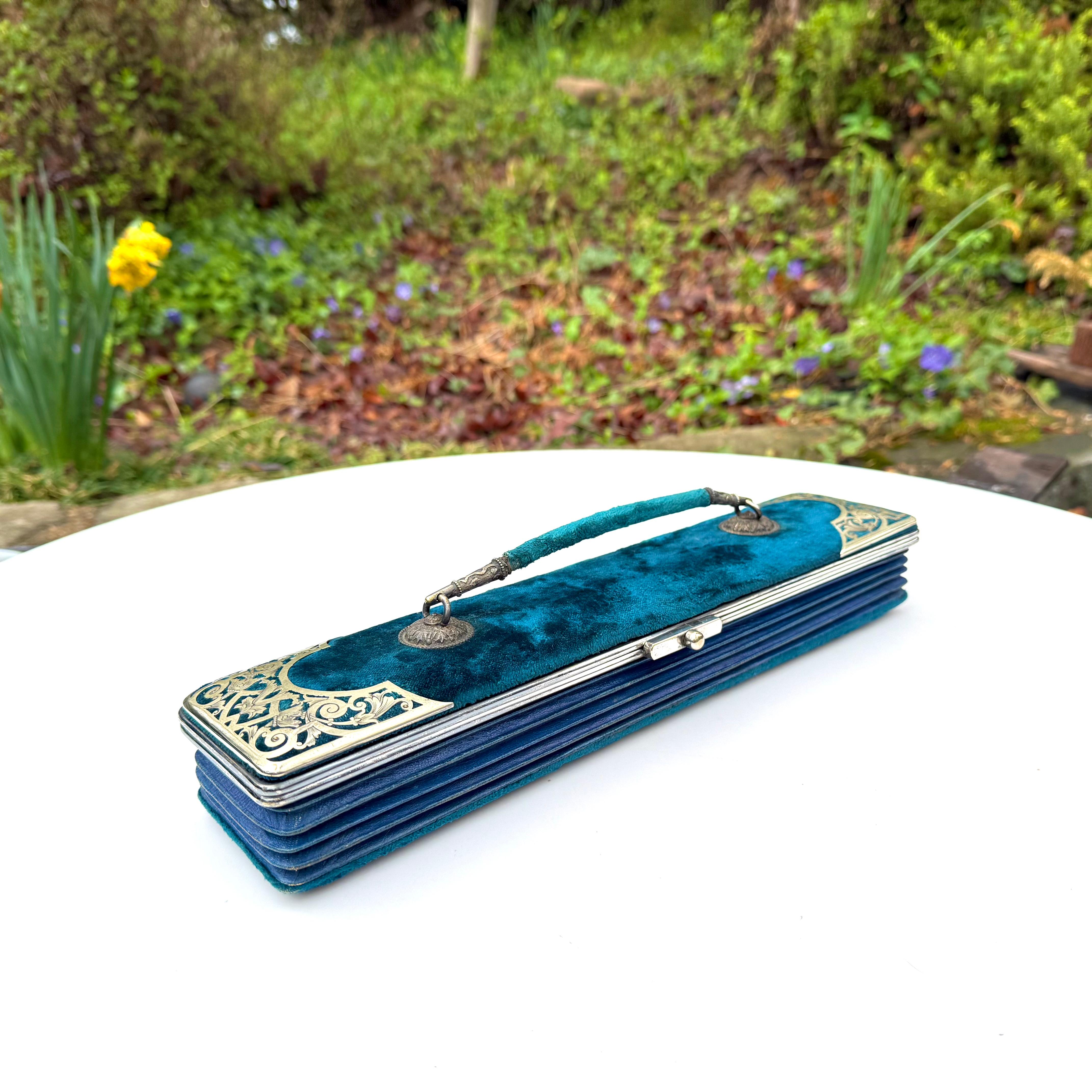 This incredible travel case is signed by August Klein, a manufacturer of leather and  fine goods. Created with Brilliant Teal Velvet, Expanding accordion Leather in Navy Blue, Sterling Silver Hardware and Adornments. 
August Klein was a