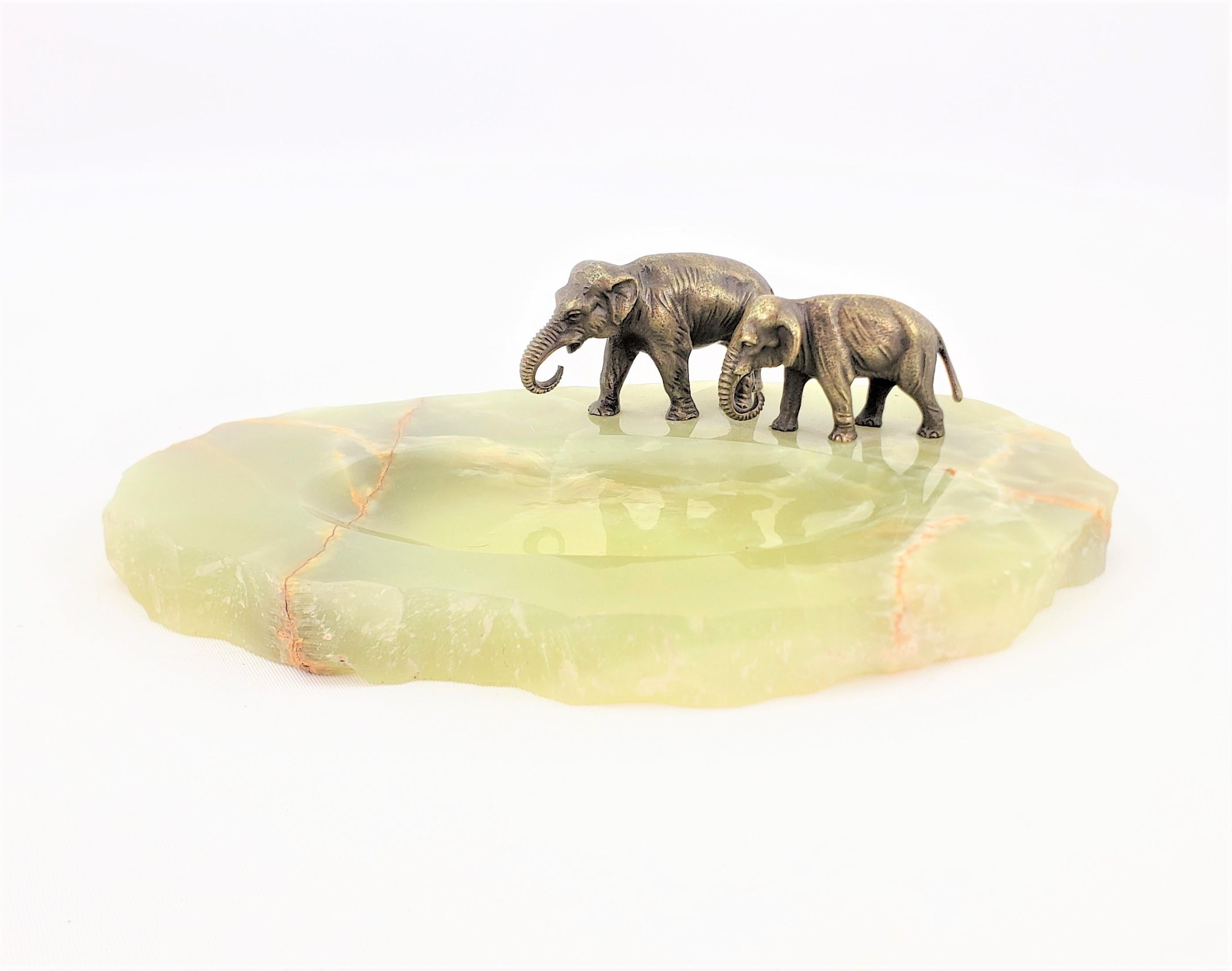 This antique decorative tray or vide-poche is unsigned, but presumed to have been made in Austria in approximately 1920 in an Art Deco style. The tray features two well executed and ornately cast and patinated elephants which are mounted on a rough