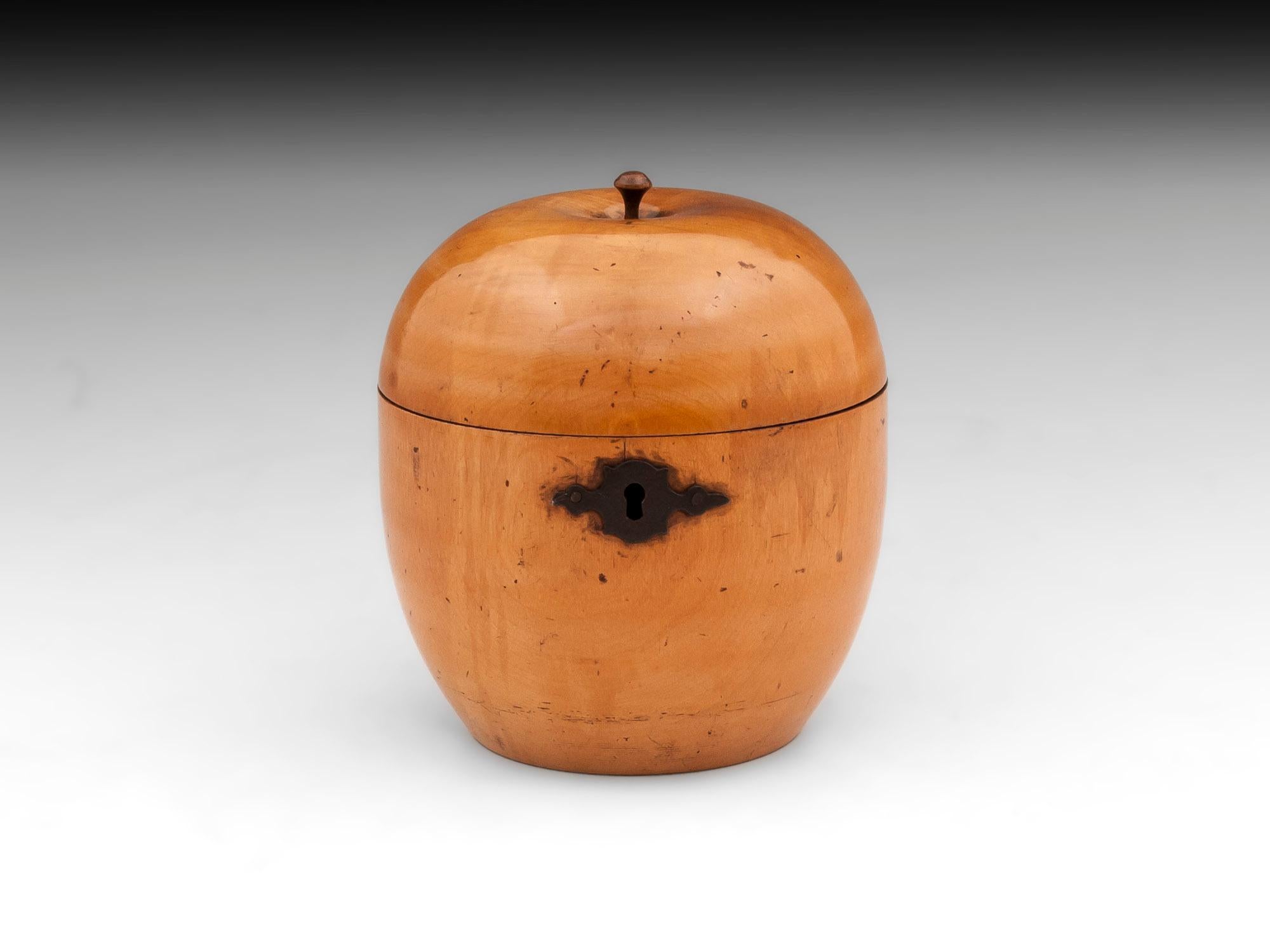 Treen apple tea caddy with great color and patination, has button stalk and ornate cut steel escutcheon.

This treen apple tea caddy still has traces of its original tin foil lining, comes with a fully working lock and tasselled key.