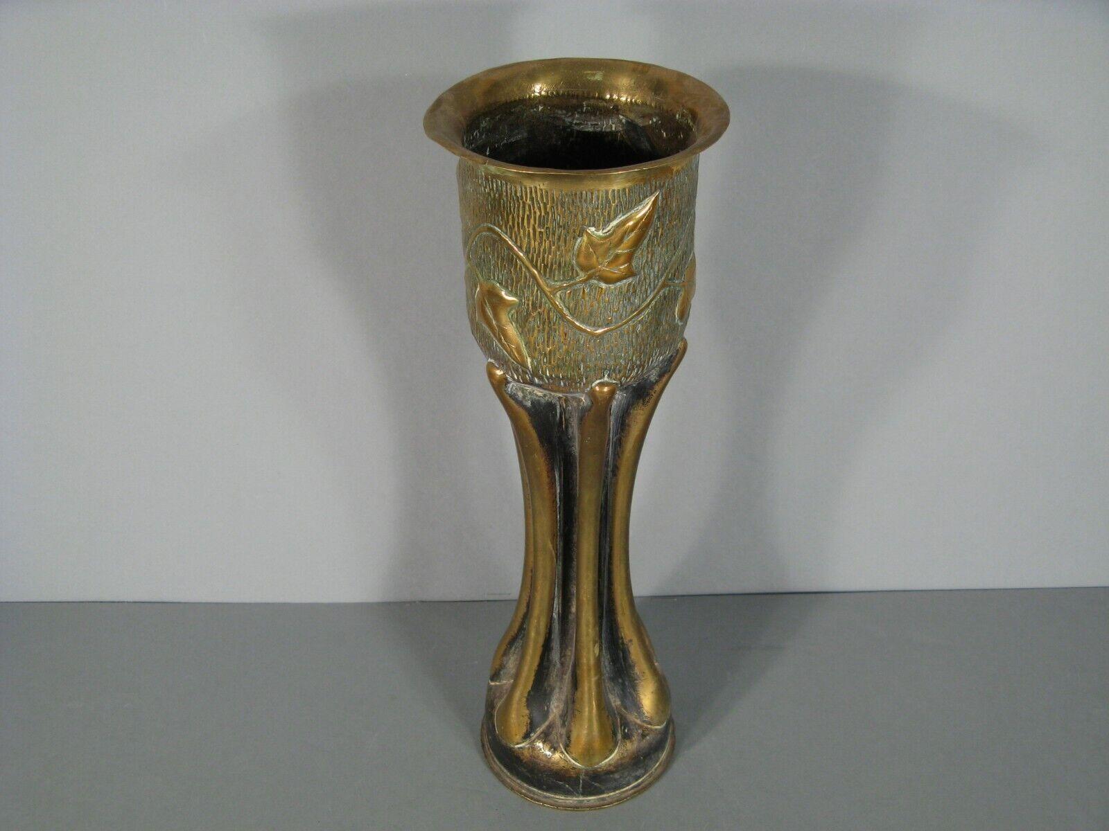 Este antiguo casquillo de latón, pieza de arte de trinchera realizada por un soldado (poilu) durante la Primera Guerra Mundial, presenta un intrincado diseño de hojas de hiedra estilizadas. Esta pieza única data del periodo de 1914-1918 y muestra el